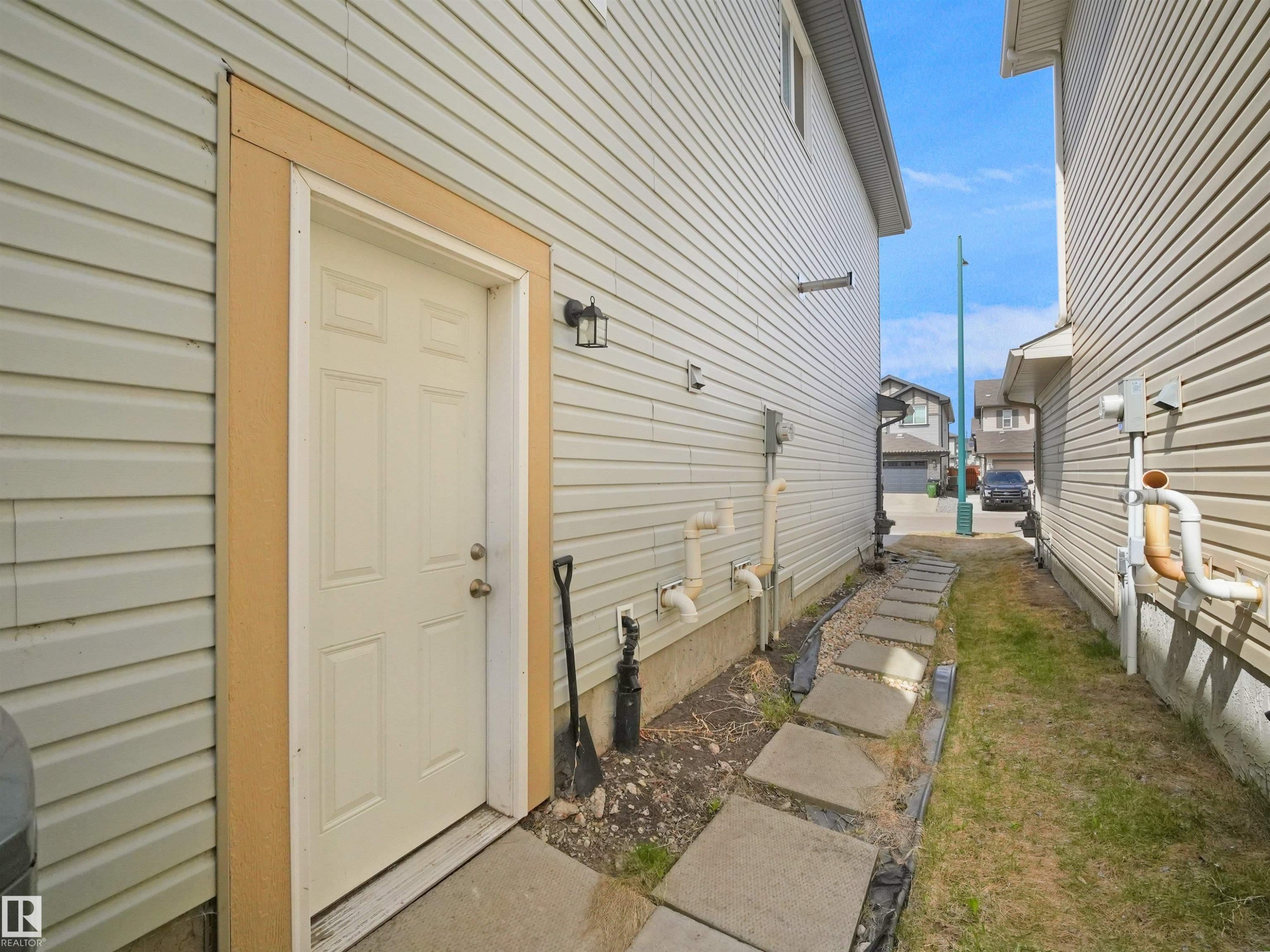 Cream-paneled exterior door with contrasting trim, complemented by an exterior wall sconce - 3247 15 Avenue Nw, Edmonton, AB - Outdoor With Exterior