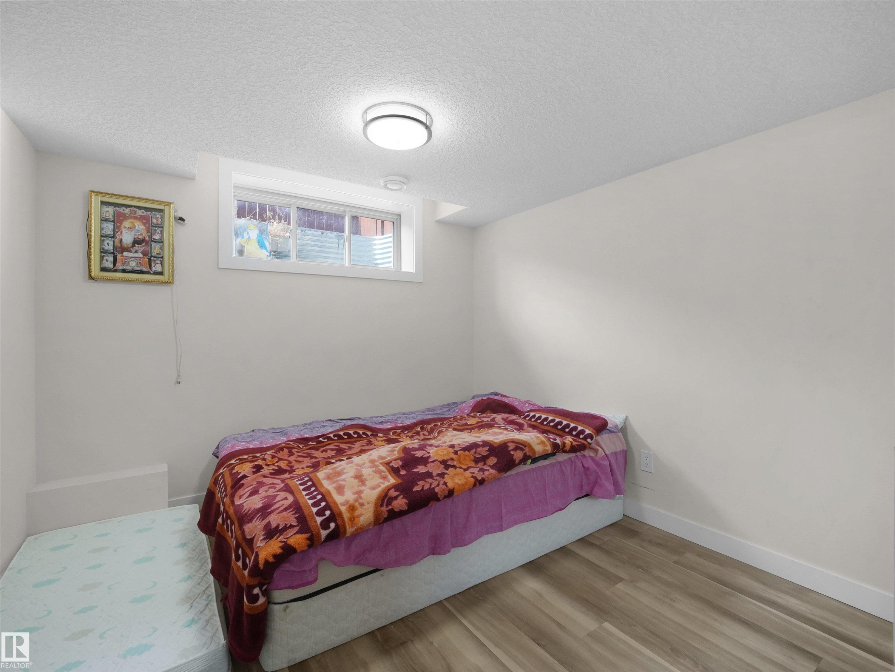Interior room featuring light wood-finish flooring, white walls, and a white ceiling with a flush-mount circular light fixture - 3247 15 Avenue Nw, Edmonton, AB - Indoor Photo Showing Bedroom