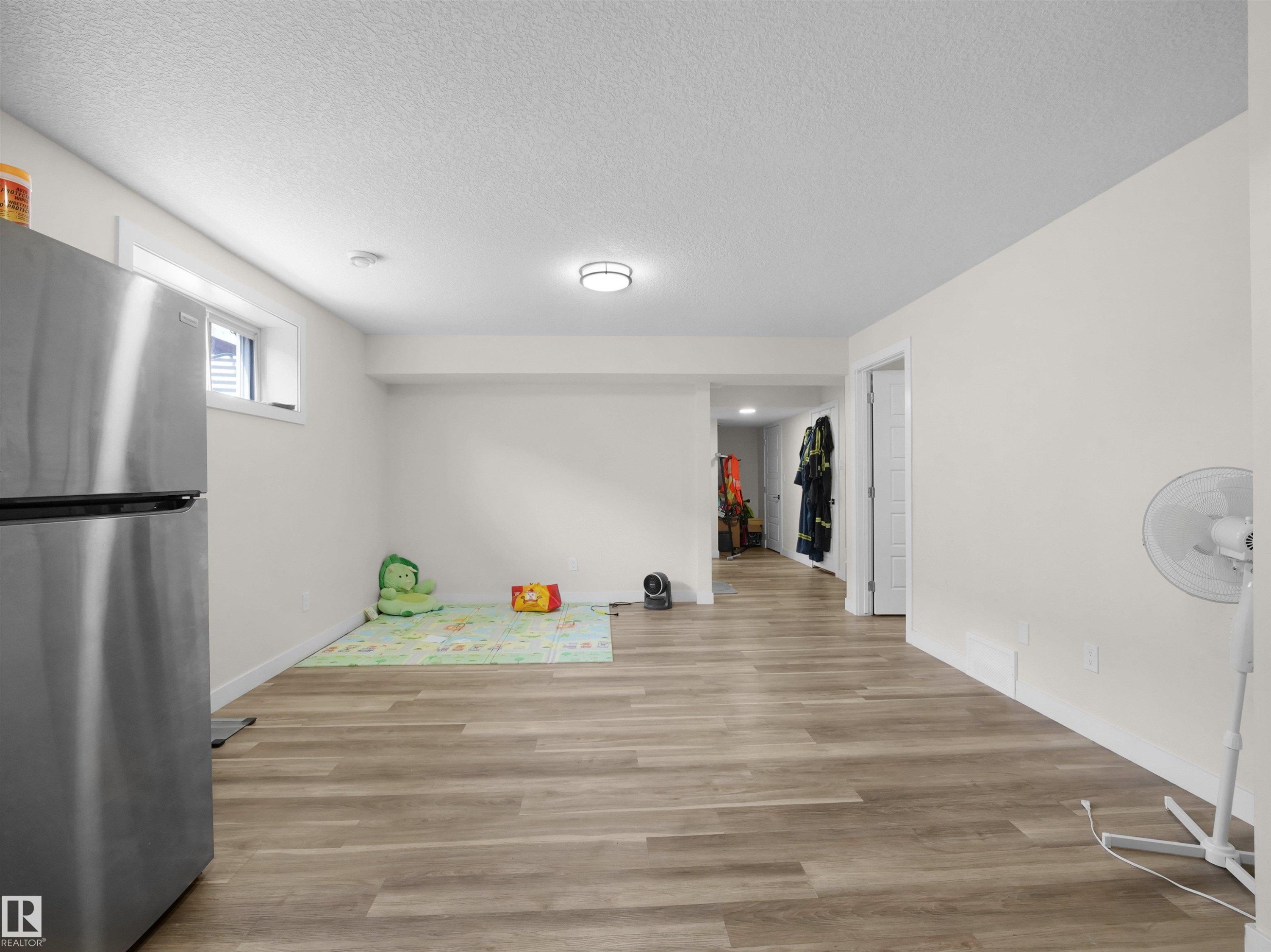Spacious room featuring wood-finish flooring, white walls, and a recessed window - 3247 15 Avenue Nw, Edmonton, AB - Indoor Photo Showing Other Room