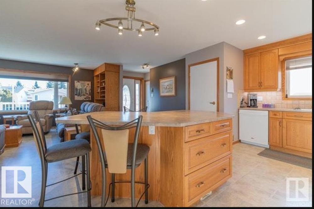 Kitchen featuring wood cabinetry, a tiled backsplash, and a built-in dishwasher - 1412 63 Street, Edmonton, AB - Indoor Photo Showing Kitchen