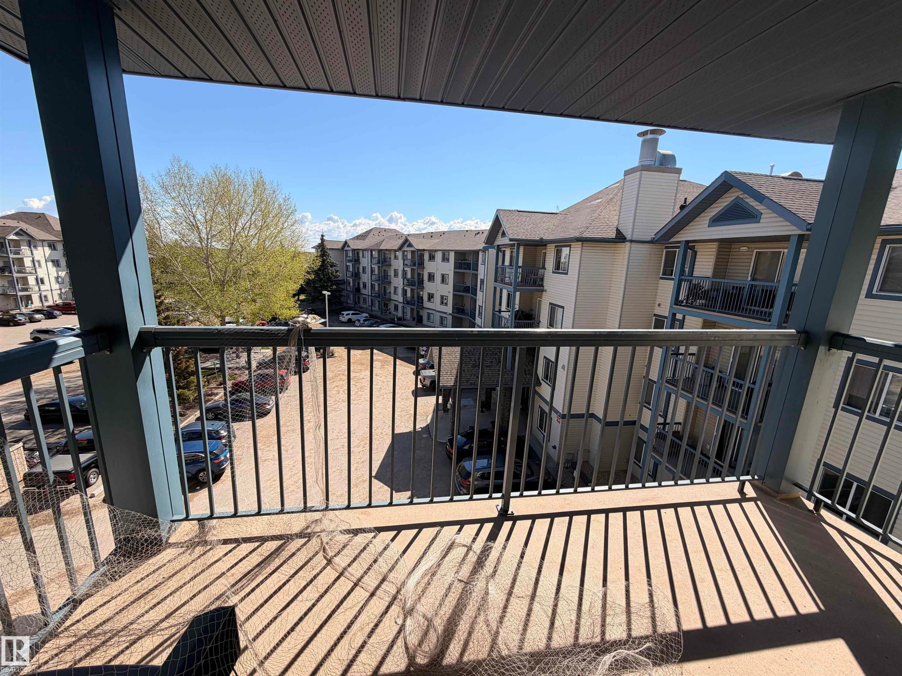 Balcony with metal railing and concrete flooring, overlooking residential buildings with pitched shingle roofs - #424 16303 95 St Nw, Edmonton, AB - Outdoor With Balcony With Exterior