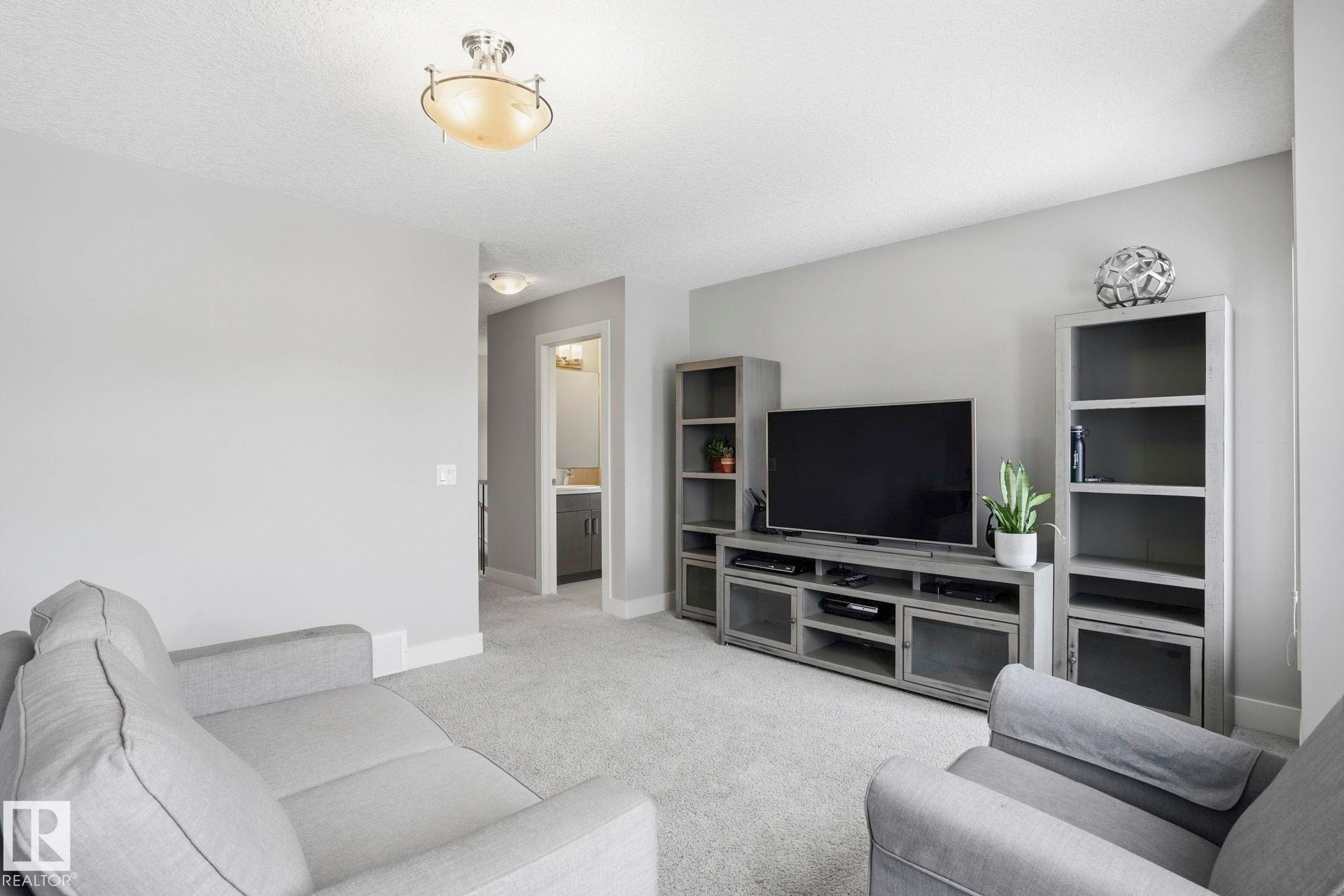 Carpeted living room with baseboards and a textured ceiling - 1915 77 Street, Edmonton, AB - Indoor Photo Showing Living Room