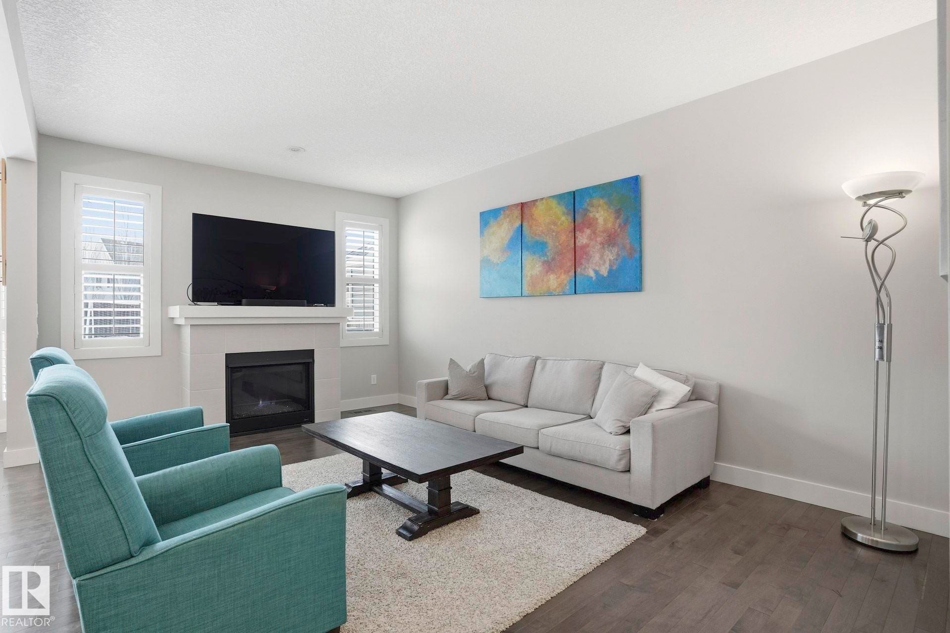 Living area with a tiled fireplace and dark wood-style flooring - 1915 77 Street, Edmonton, AB - Indoor Photo Showing Living Room With Fireplace