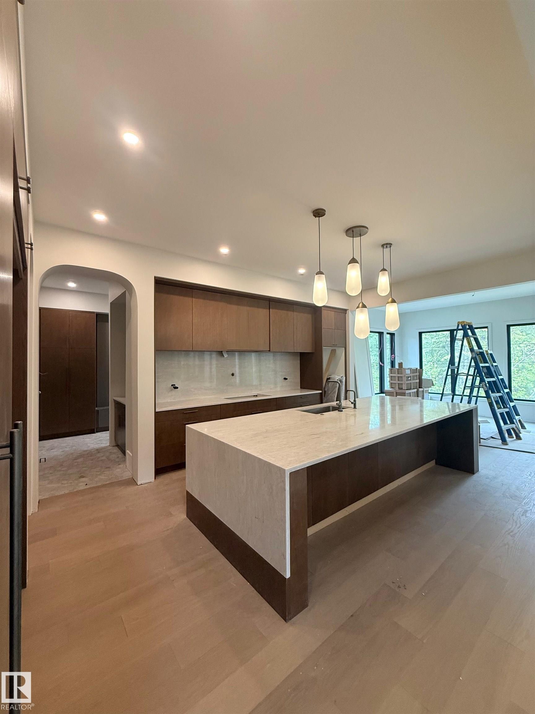 Kitchen featuring a waterfall island with stone countertop, dark wood-finish cabinetry, and pendant lighting - 14702 Park Drive, Edmonton, AB - Indoor Photo Showing Kitchen