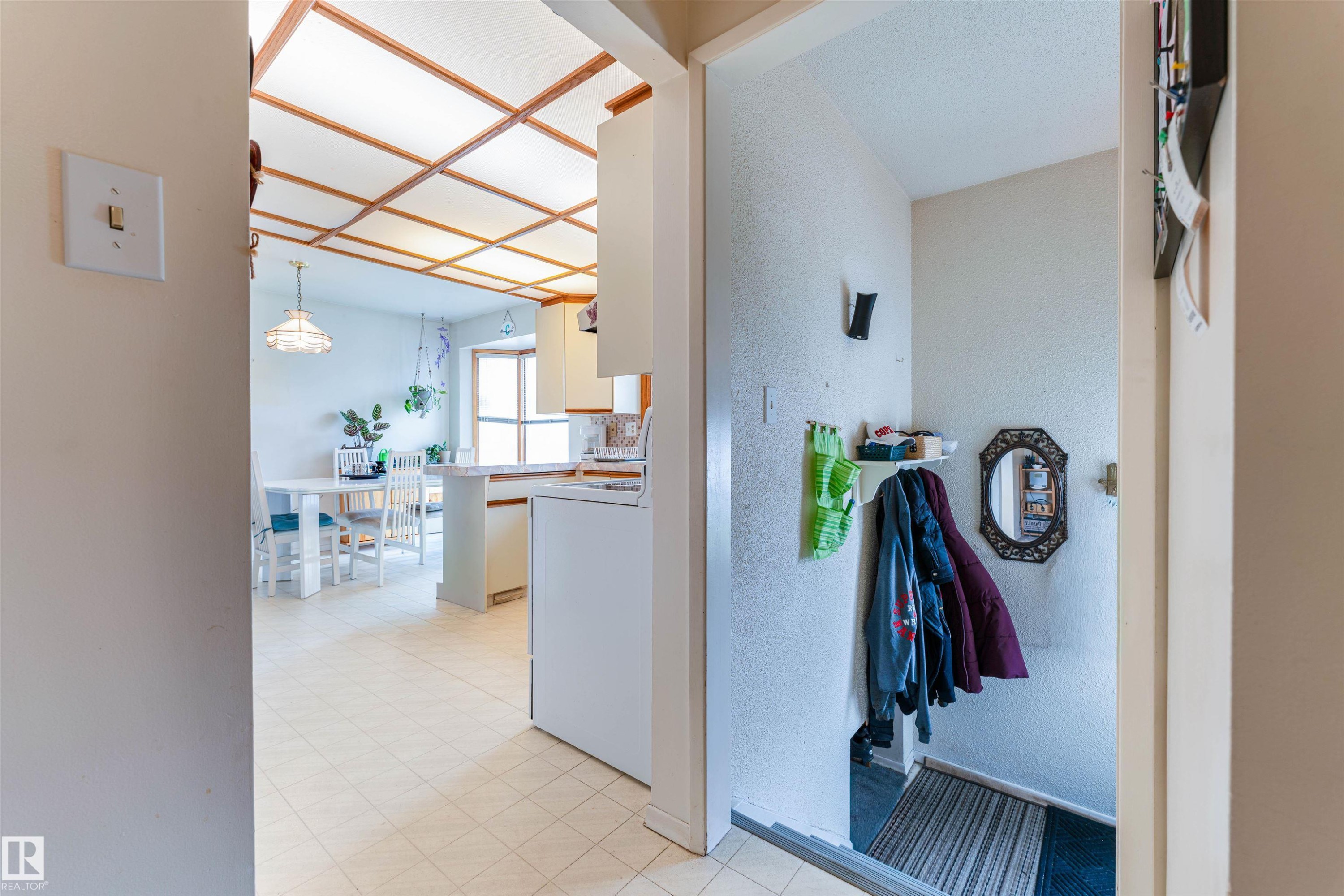 The main living area features a coffered ceiling, a dining space with a window, and a kitchen with white cabinetry and a built-in oven - 13231 74 Street, Edmonton, AB - Indoor