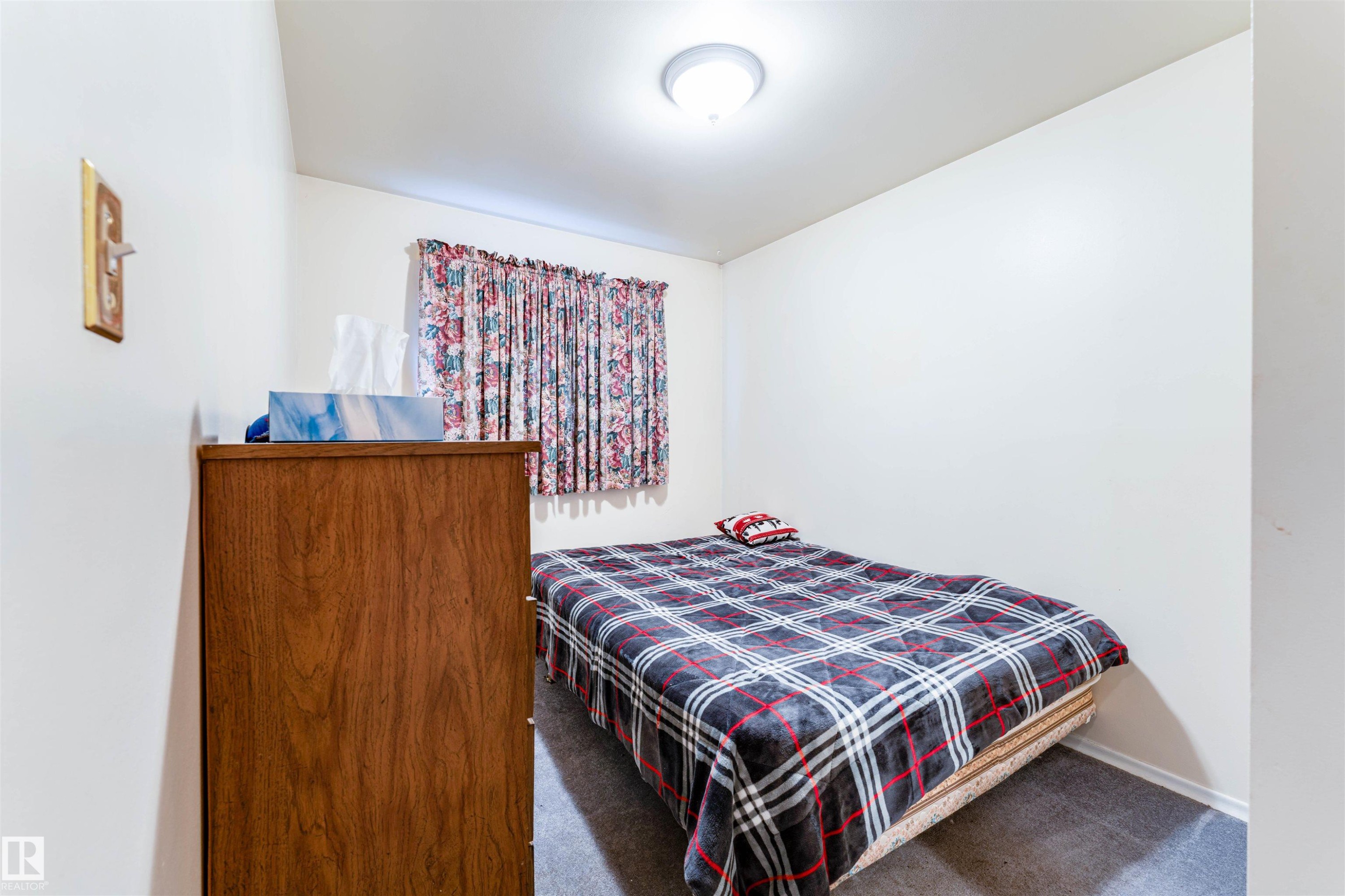White-painted interior room with a flush-mount ceiling light fixture, carpeting, and a window with floral curtains - 13231 74 Street, Edmonton, AB - Indoor Photo Showing Bedroom