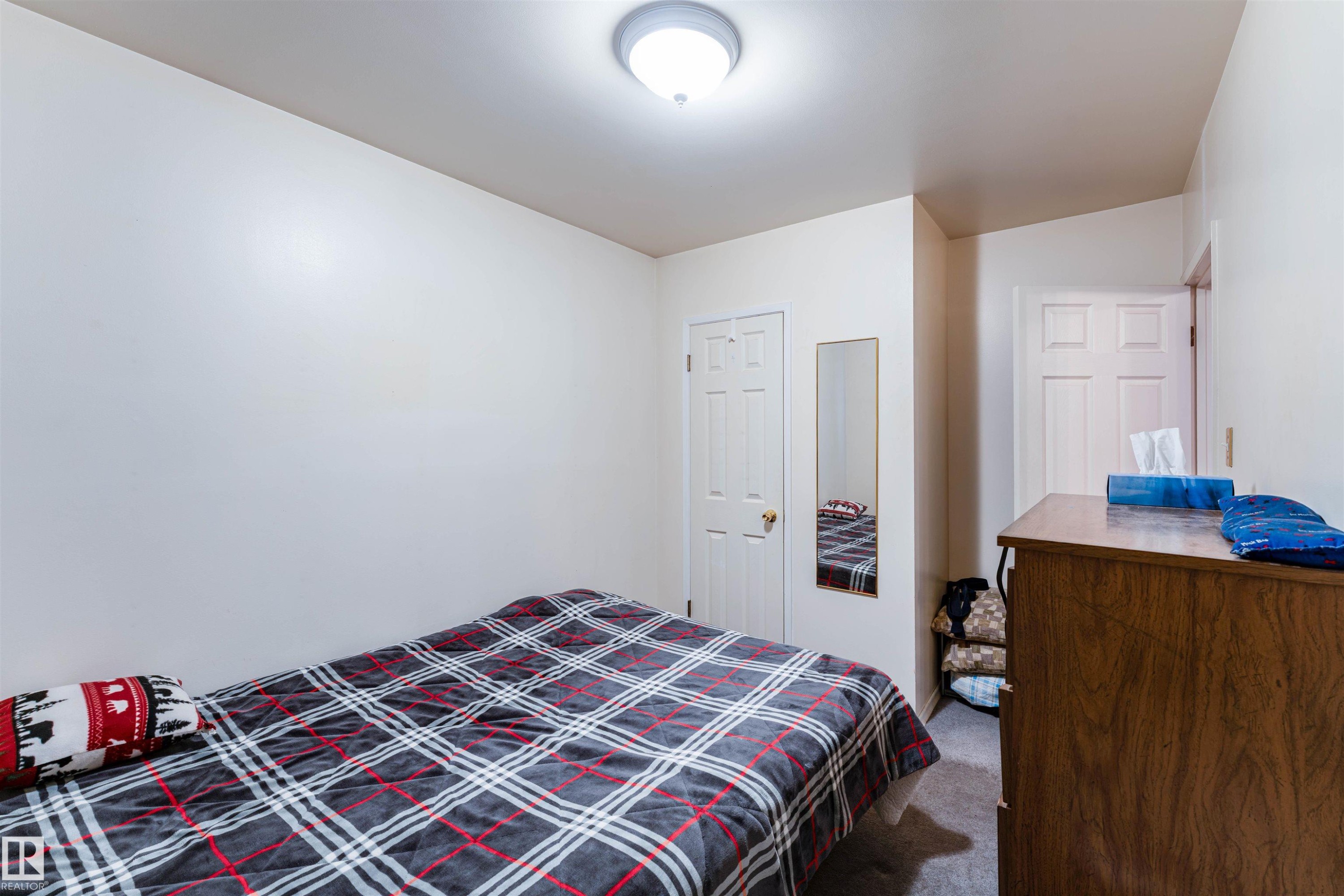 Cozy room featuring neutral wall tones, a flush-mount ceiling light fixture, and a built-in closet with a paneled door - 13231 74 Street, Edmonton, AB - Indoor Photo Showing Bedroom