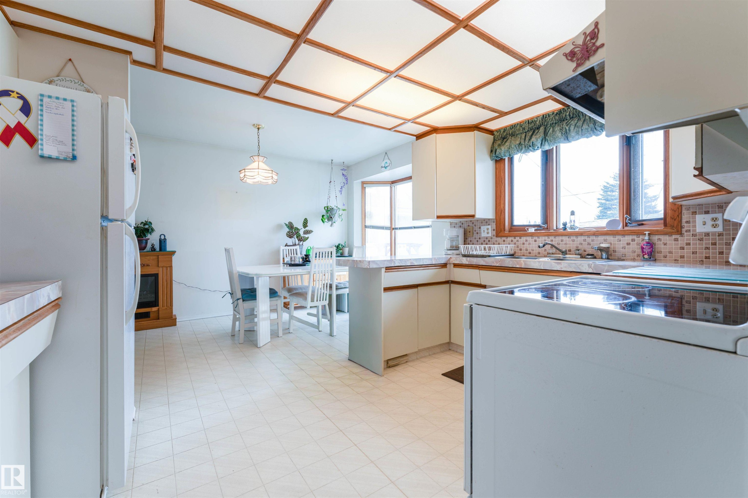 Kitchen featuring white cabinetry, tile backsplash, laminate countertops, and a full-size electric range - 13231 74 Street, Edmonton, AB - Indoor