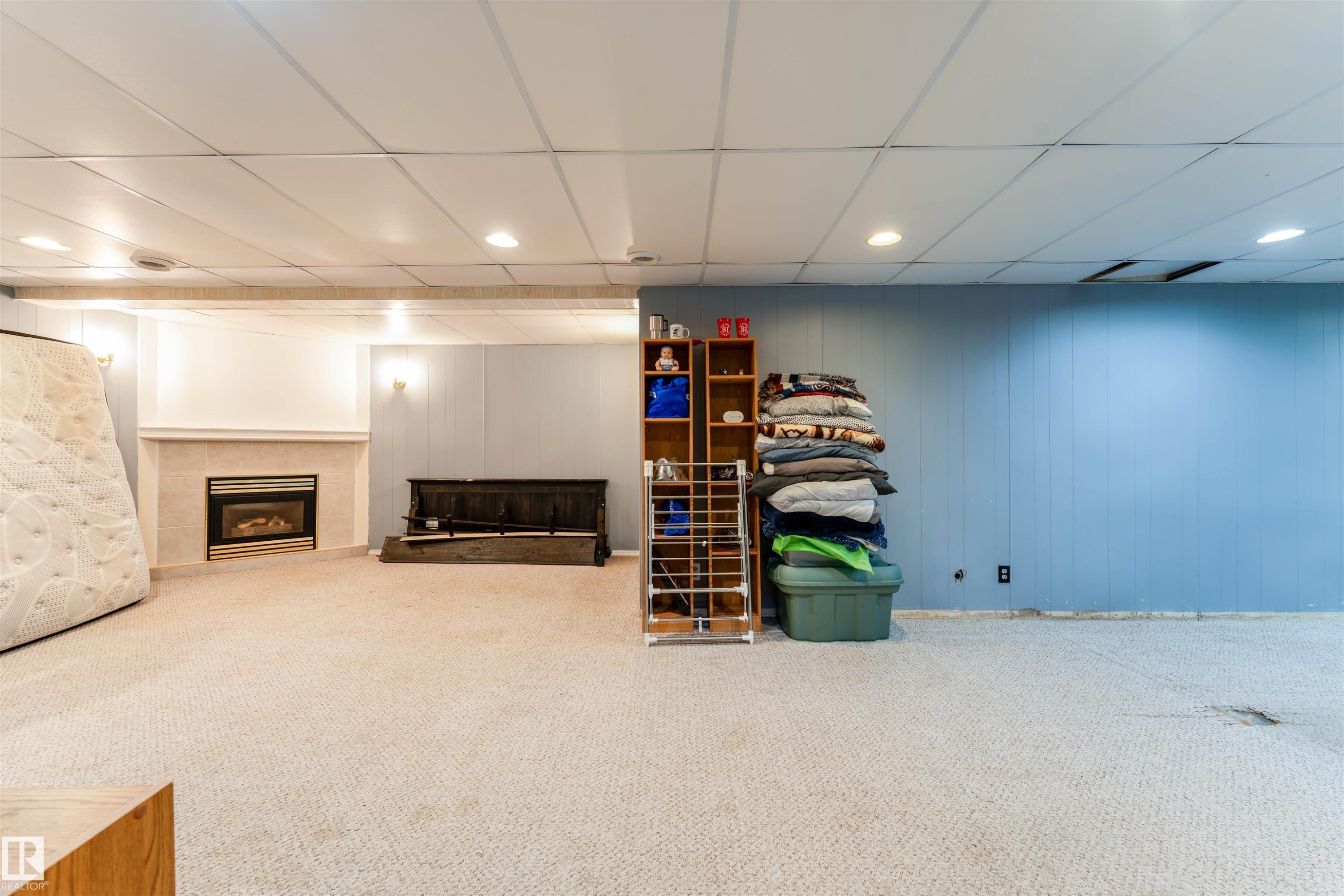 Carpeted room featuring a fireplace with a stone surround and mantel, recessed lighting, and a drop ceiling - 13231 74 Street, Edmonton, AB - Indoor Photo Showing Basement With Fireplace