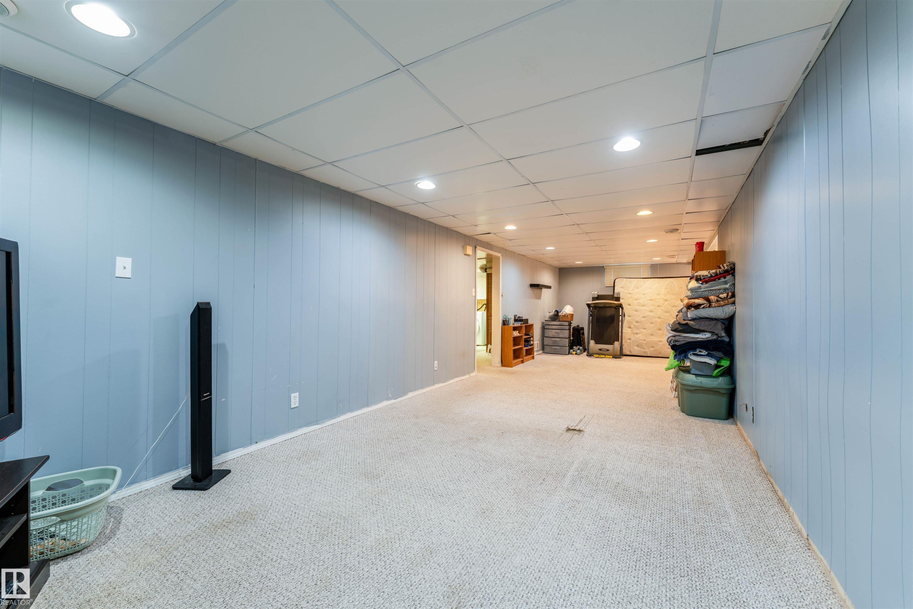 Finished lower level featuring light blue vertical paneling, recessed lighting, and light-toned carpet flooring - 13231 74 Street, Edmonton, AB - Indoor