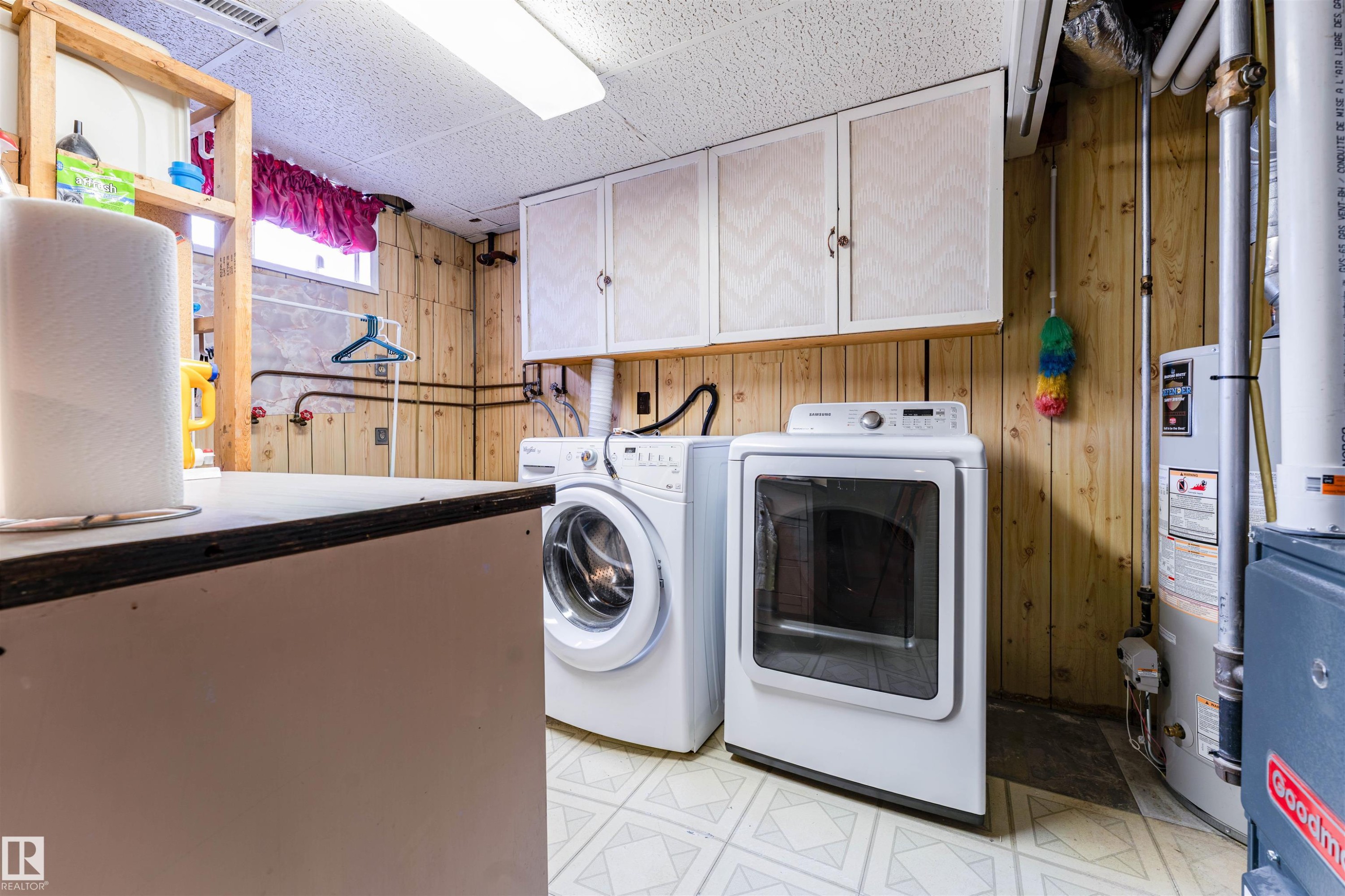 Utility space featuring wood paneling, overhead cabinetry, and patterned vinyl flooring - 13231 74 Street, Edmonton, AB - Indoor Photo Showing Laundry Room