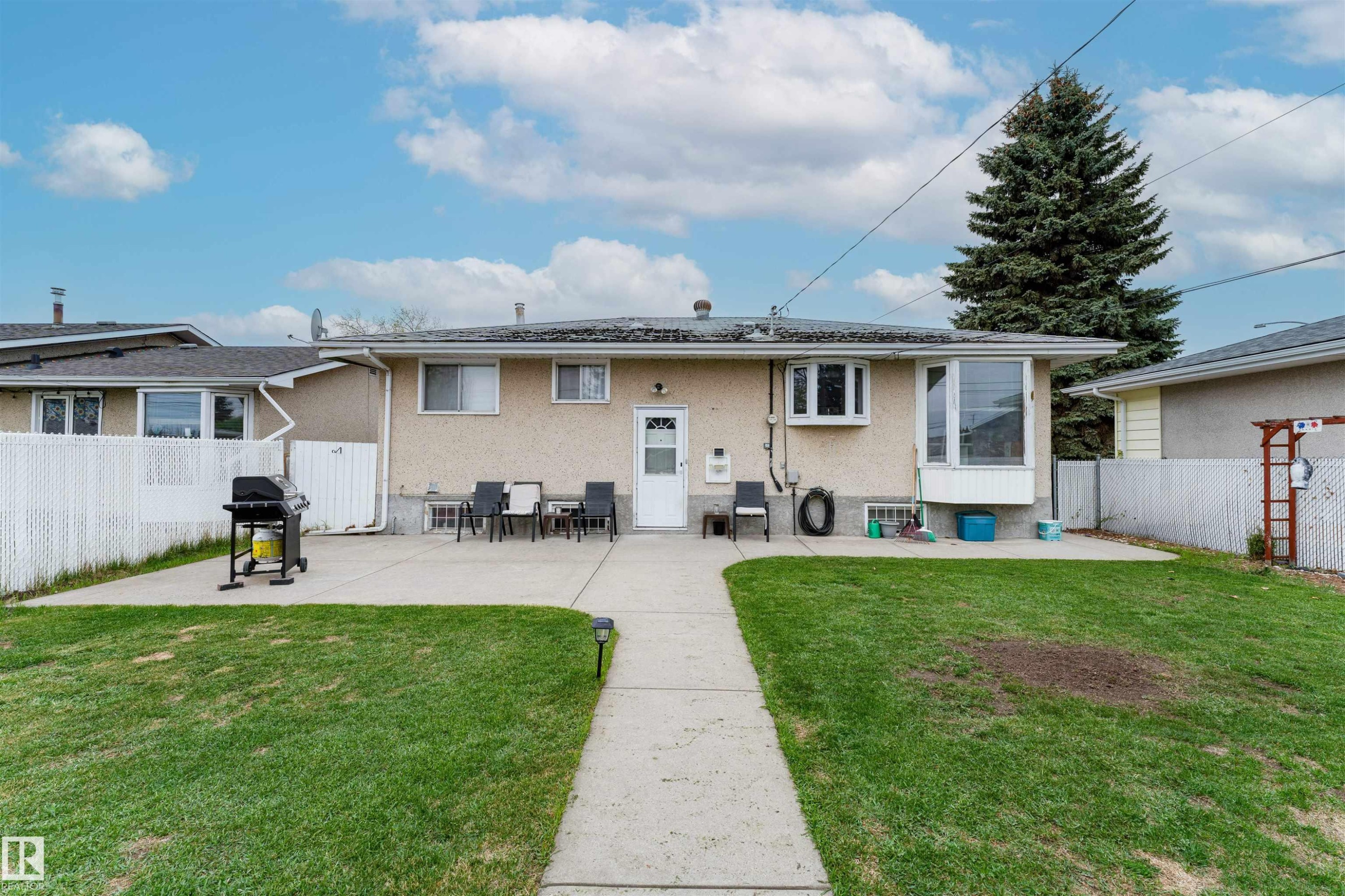 Rear exterior featuring stucco siding, a large bay window, and a white entrance door - 13231 74 Street, Edmonton, AB - Outdoor