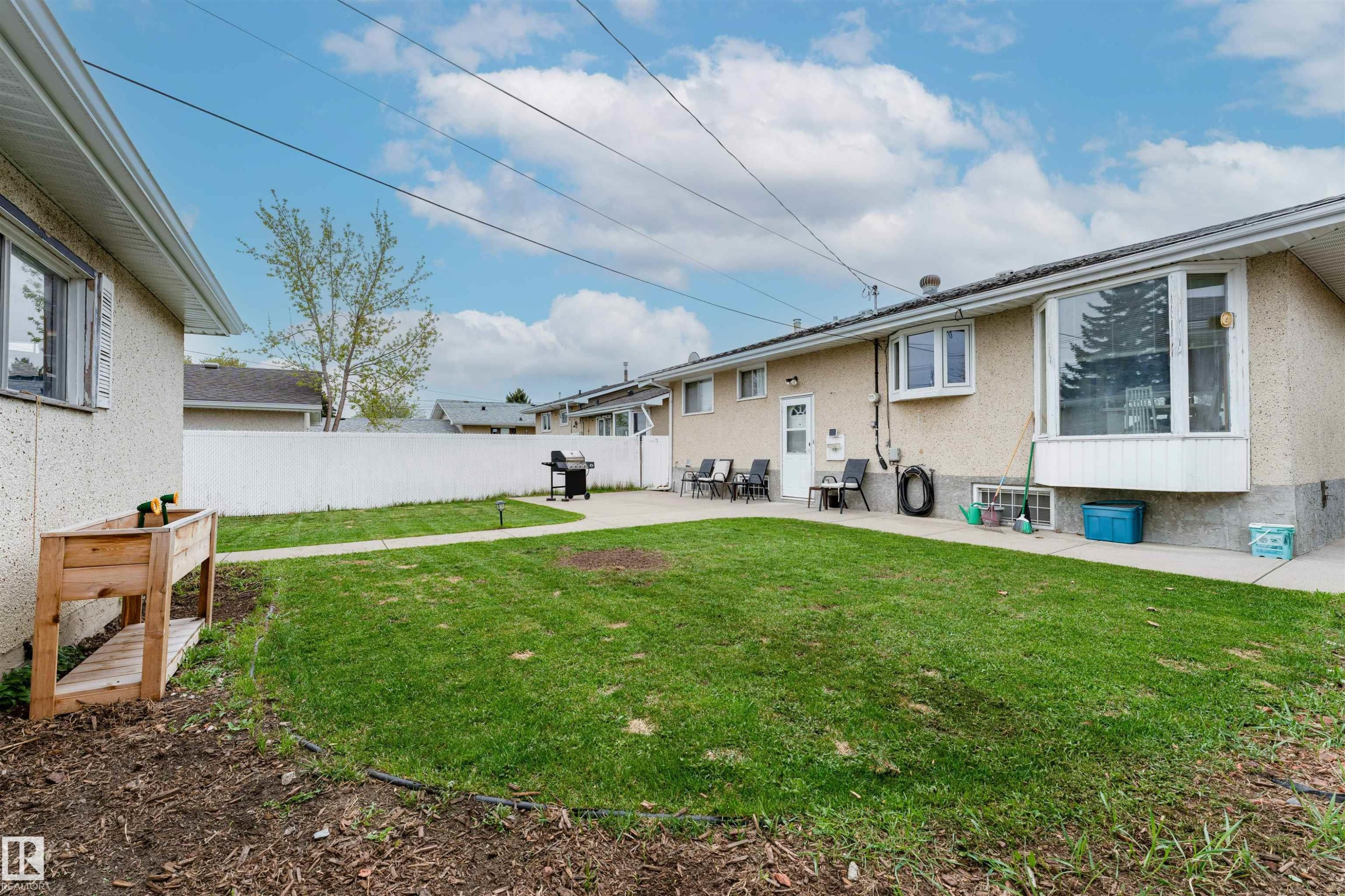 Expansive backyard featuring a large concrete patio, a manicured lawn, and a white privacy fence - 13231 74 Street, Edmonton, AB - Outdoor