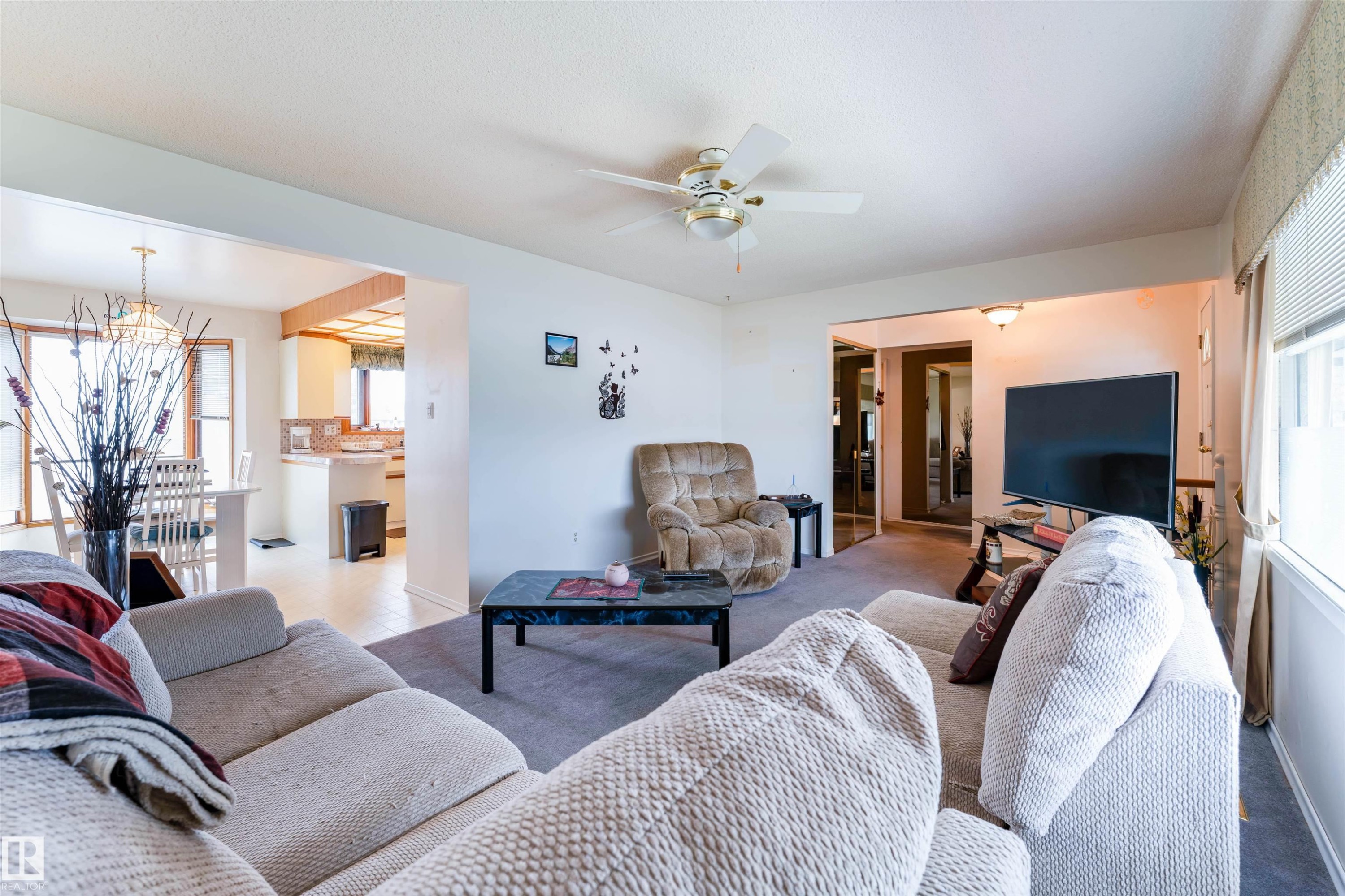 Living area featuring neutral-tone carpeting, a ceiling fan with integrated lighting, and white baseboards - 13231 74 Street, Edmonton, AB - Indoor Photo Showing Living Room