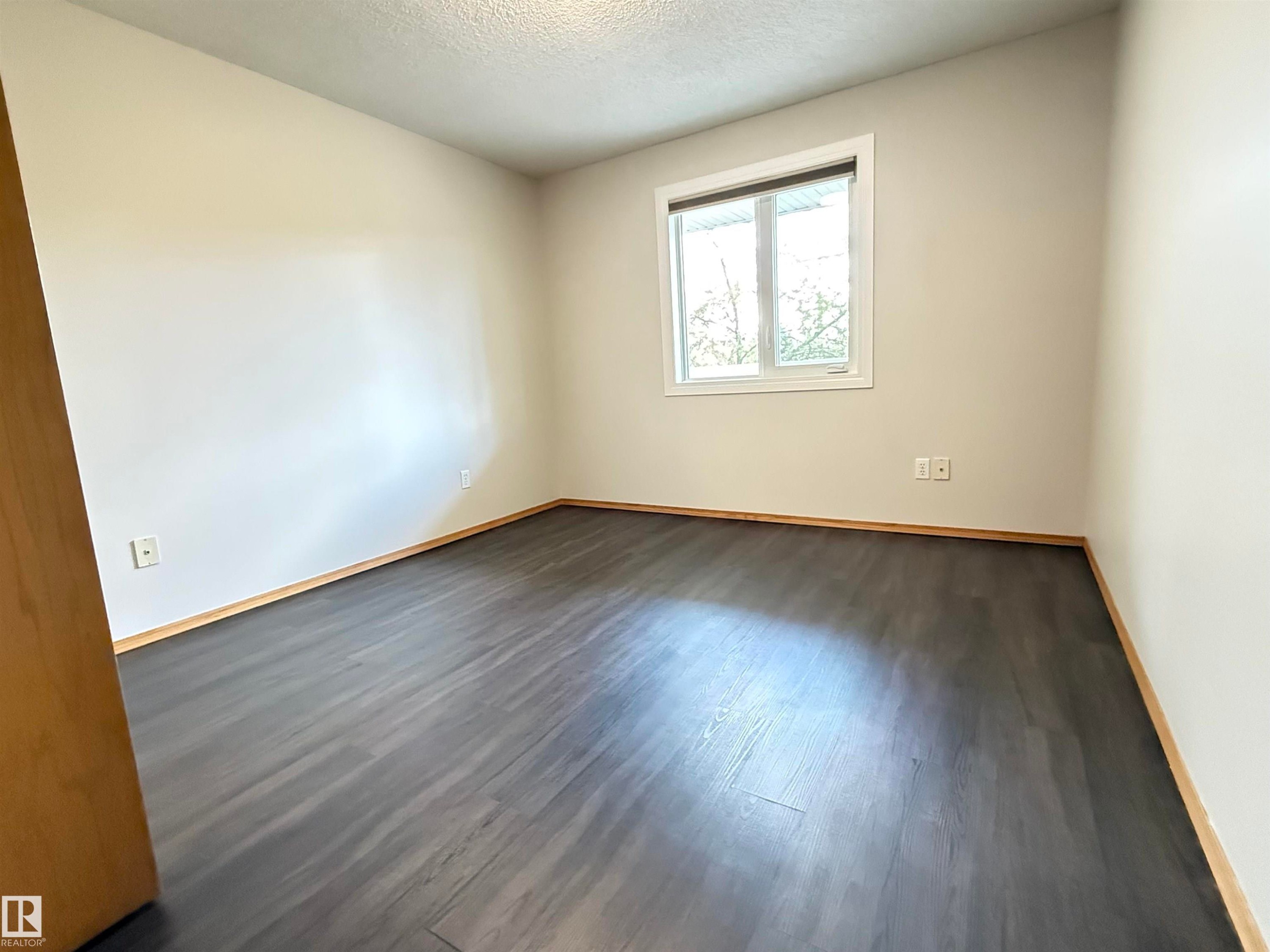 Room featuring dark wood-finish flooring and light-toned walls - #309 10610 76 St Nw, Edmonton, AB - Indoor Photo Showing Other Room