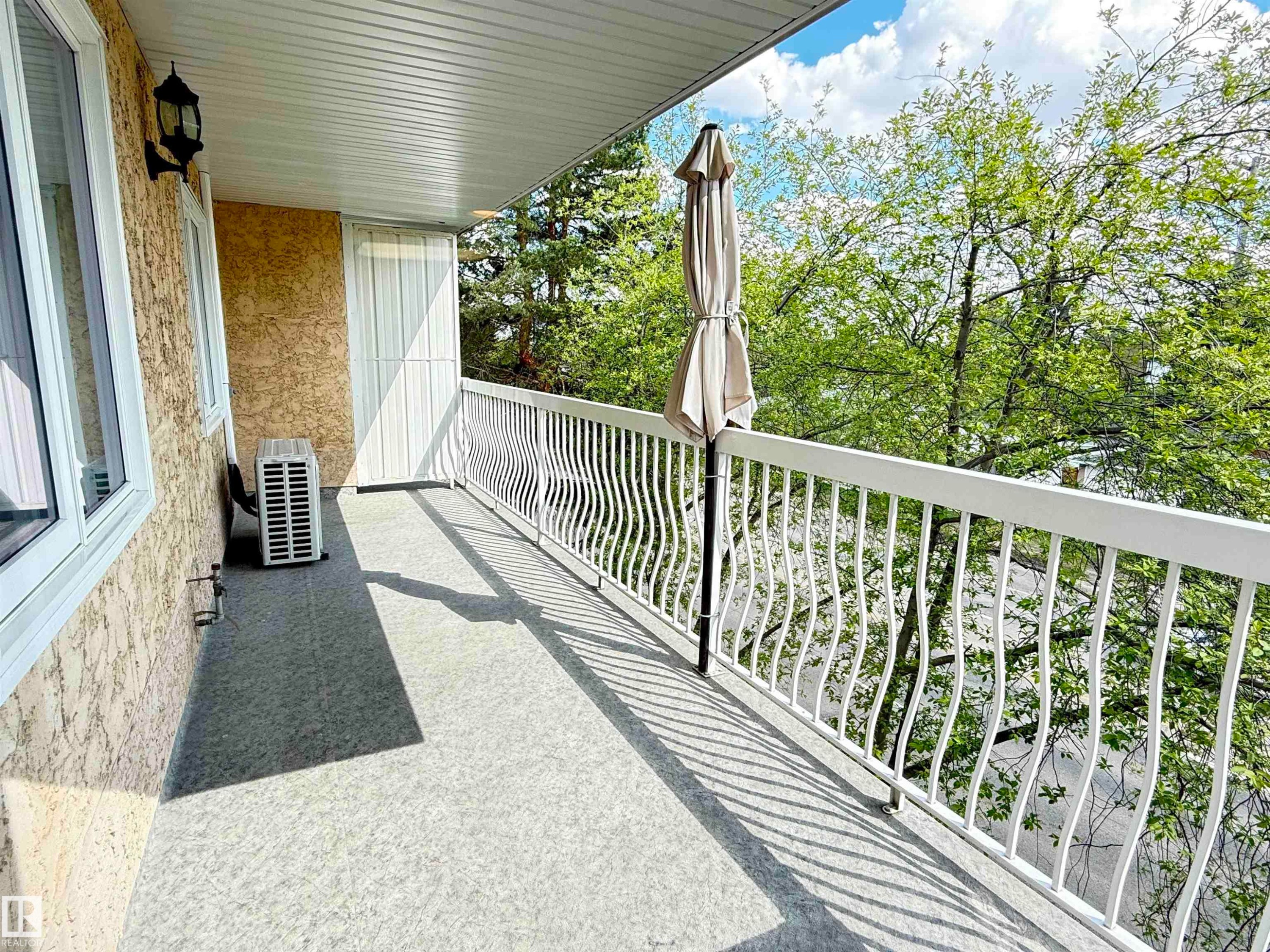 Balcony featuring a textured exterior wall, white window frames, and decorative white metal railings - #309 10610 76 St Nw, Edmonton, AB - Outdoor With Exterior