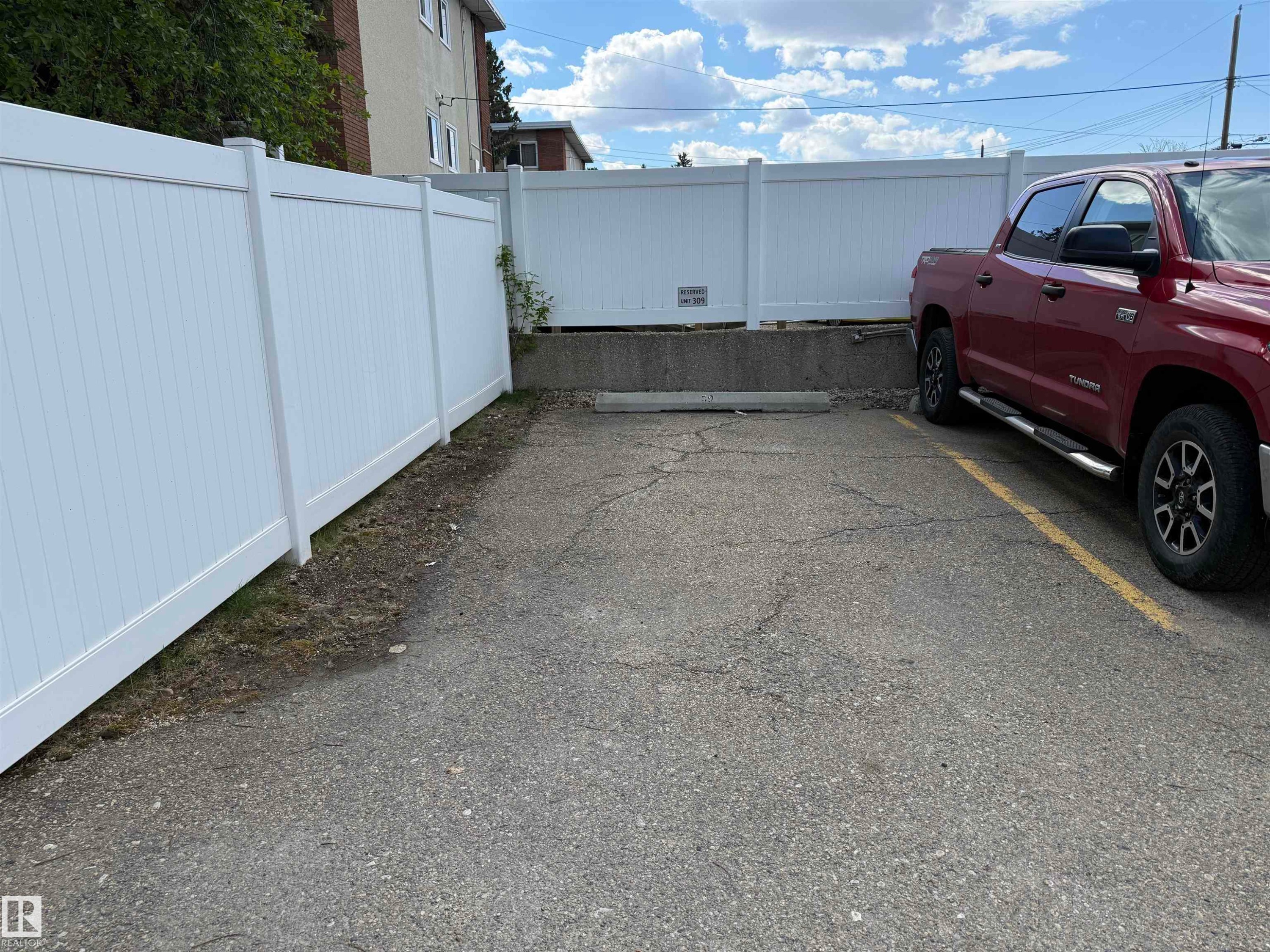 Paved parking area featuring white privacy fencing - #309 10610 76 St Nw, Edmonton, AB - Outdoor