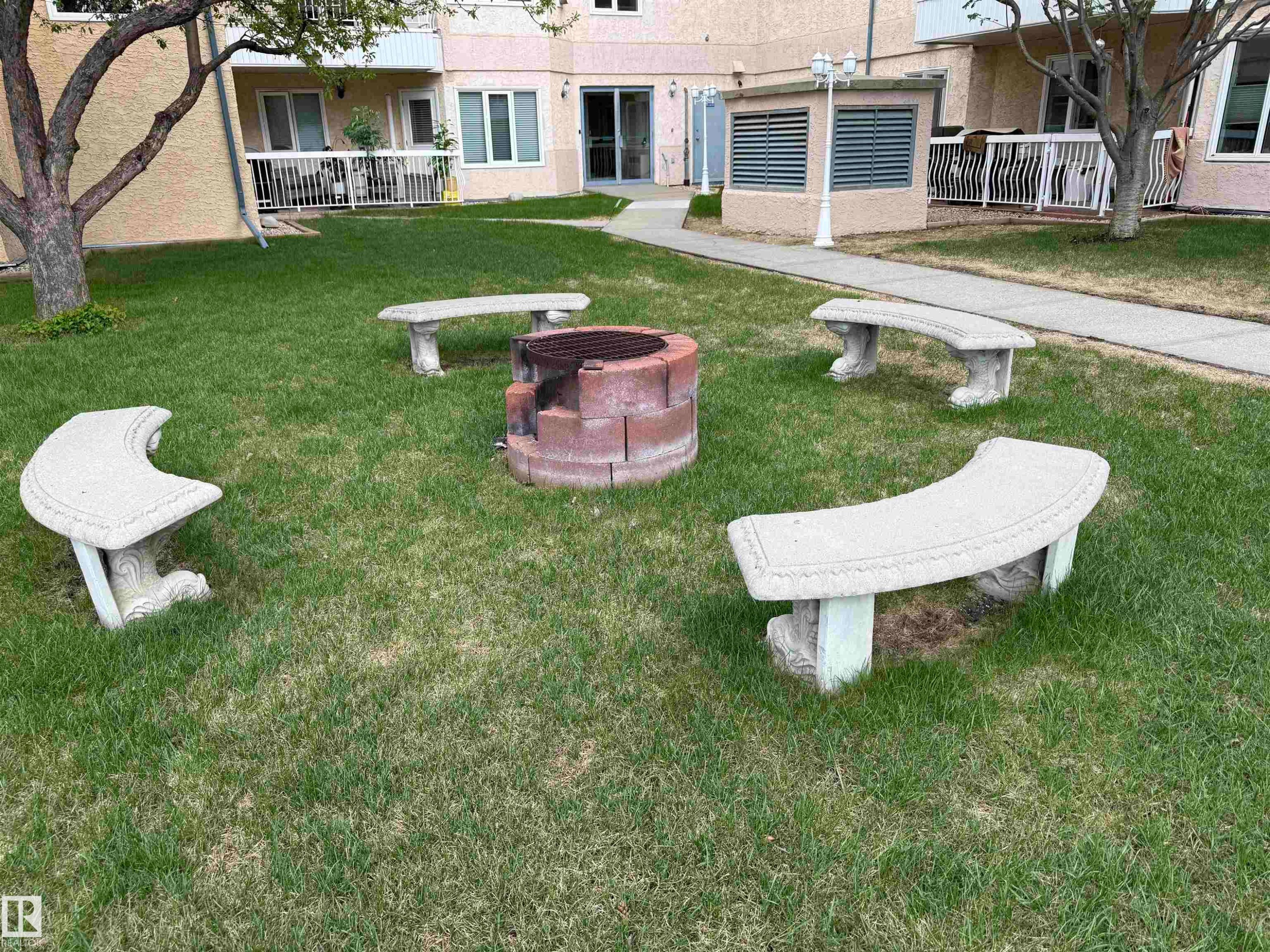 Central fire pit area featuring four curved stone benches - #309 10610 76 St Nw, Edmonton, AB - Outdoor