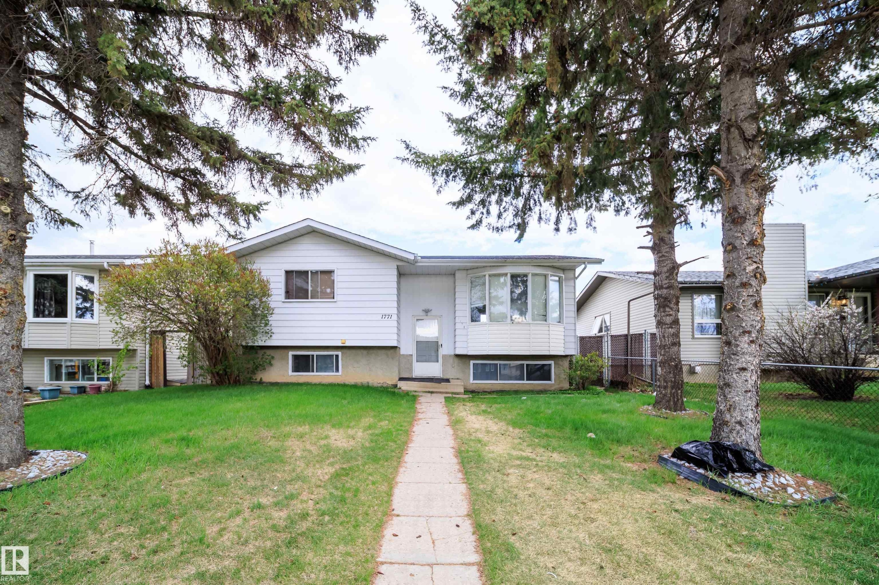 Front exterior featuring a concrete walkway, bay window, white siding, and mature trees - 1771 37 Street, Edmonton, AB - Outdoor With Facade
