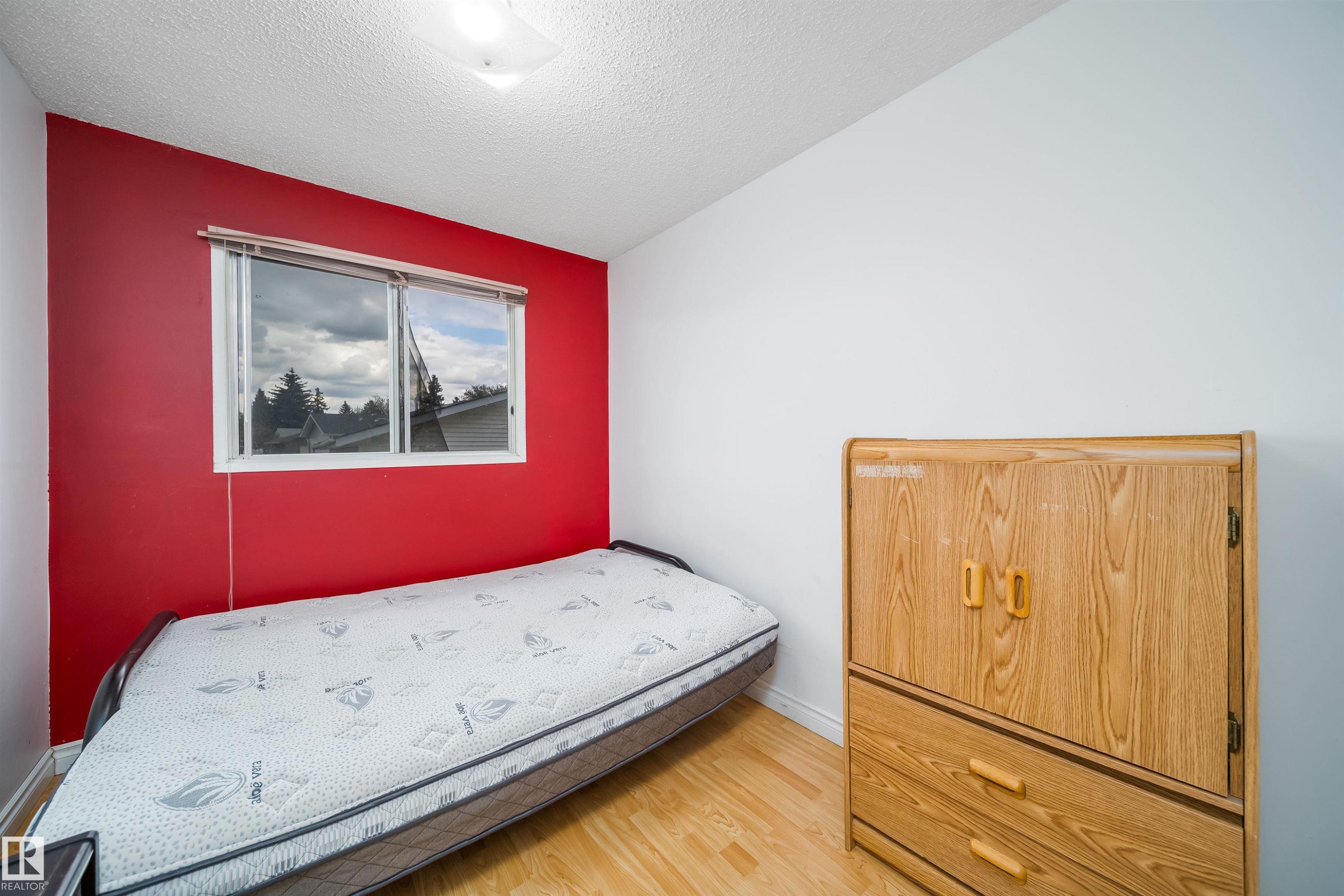 Room featuring a window with blinds, wood-finish flooring, white baseboards, and a flush-mount ceiling light fixture - 1771 37 Street, Edmonton, AB - Indoor Photo Showing Bedroom