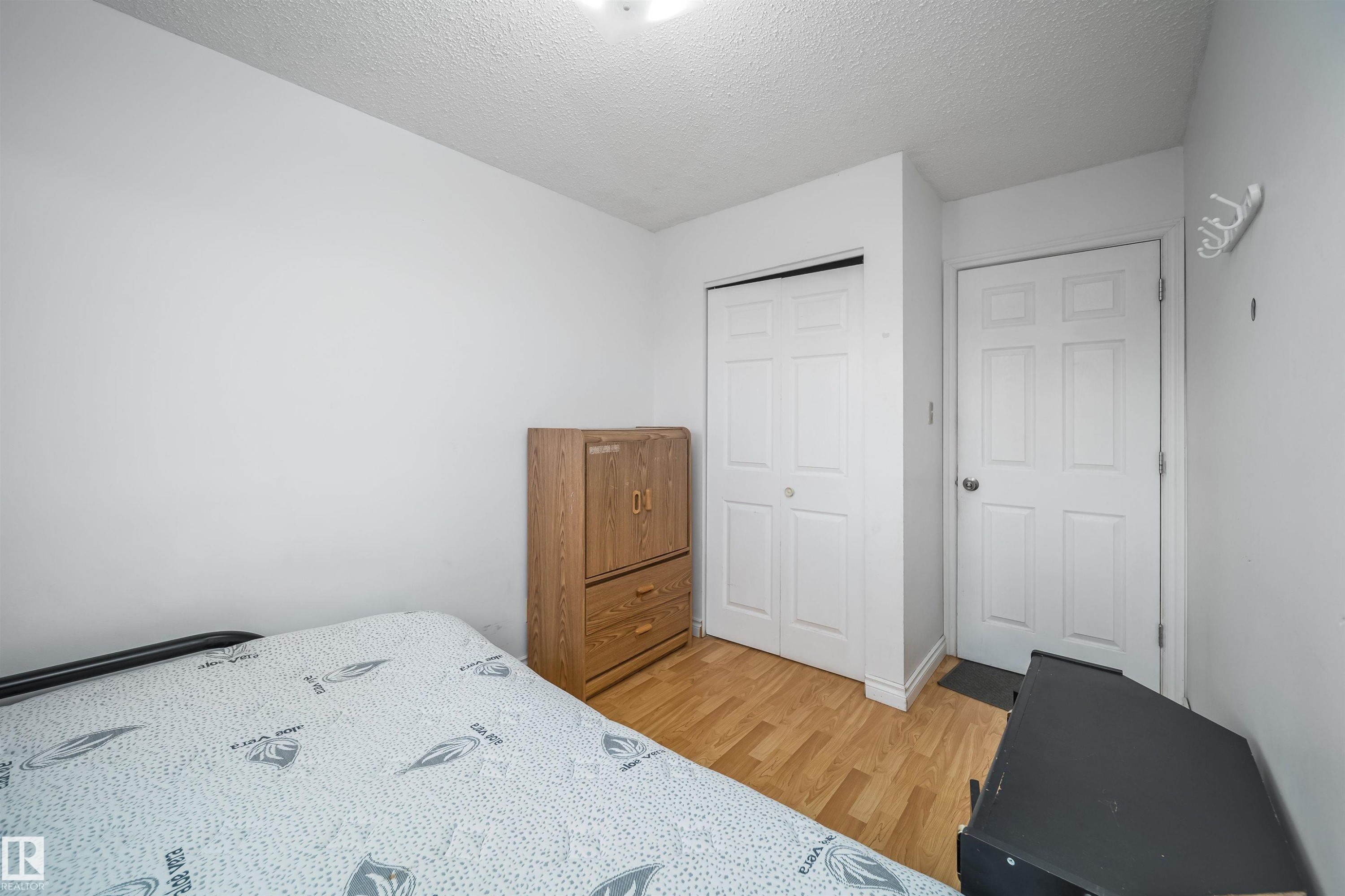 Interior room featuring wood-finish flooring, a bi-fold closet door, a paneled door, and neutral wall tones - 1771 37 Street, Edmonton, AB - Indoor Photo Showing Bedroom
