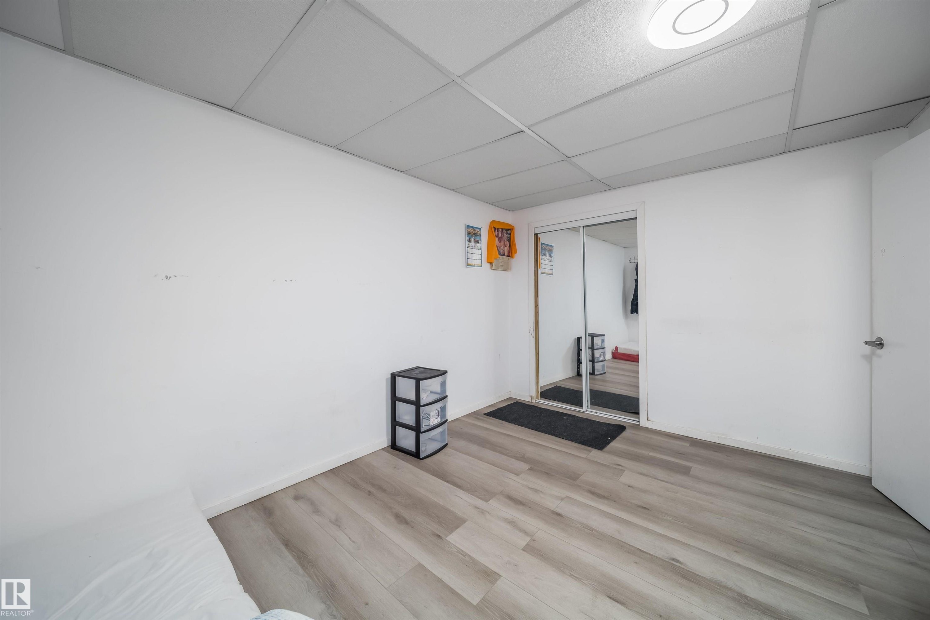 Spacious room featuring light wood-finish flooring, white walls, and a drop ceiling with recessed lighting - 1771 37 Street, Edmonton, AB - Indoor