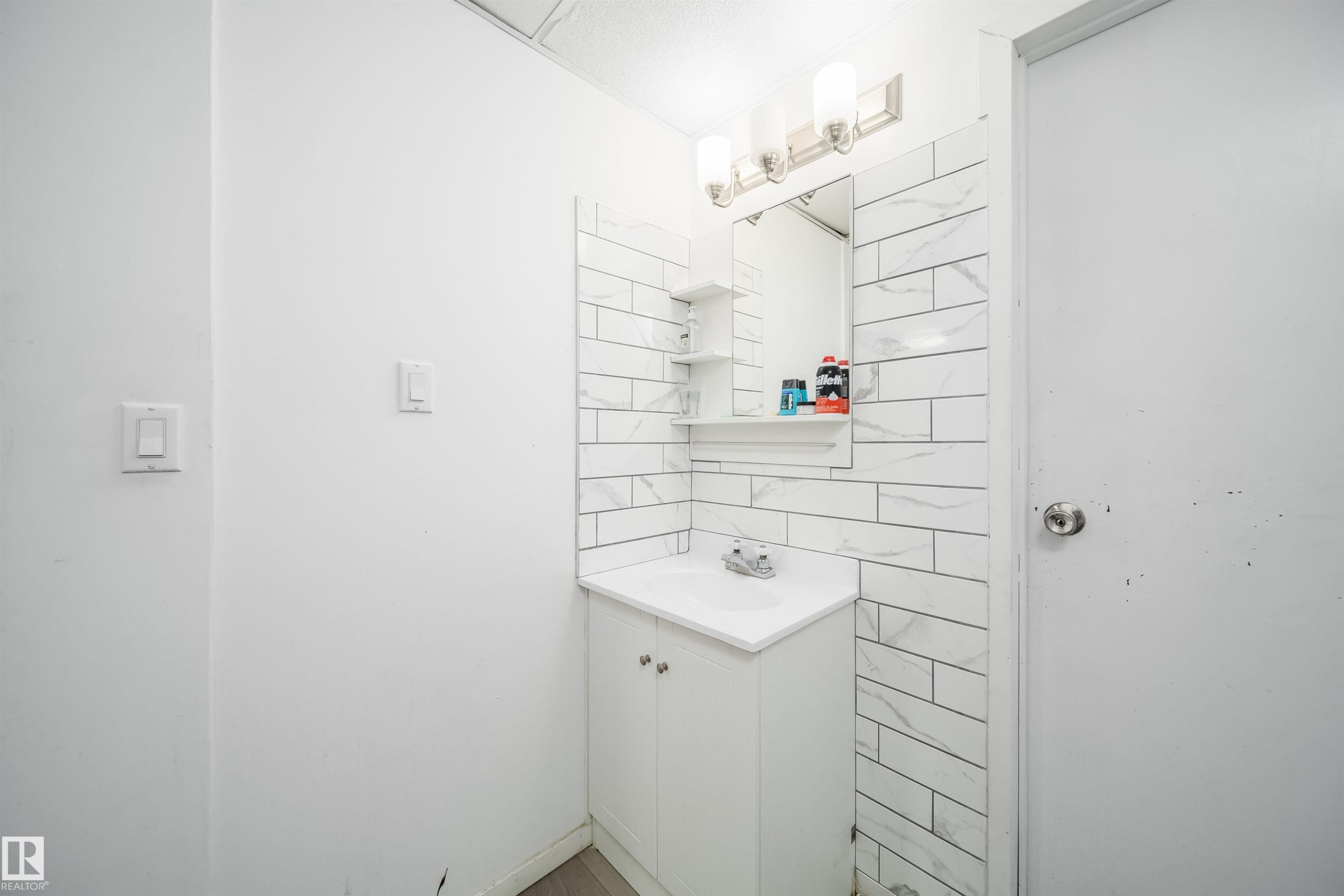 Bathroom vanity featuring a white cabinet, integrated sink, and brushed nickel faucet - 1771 37 Street, Edmonton, AB - Indoor Photo Showing Bathroom