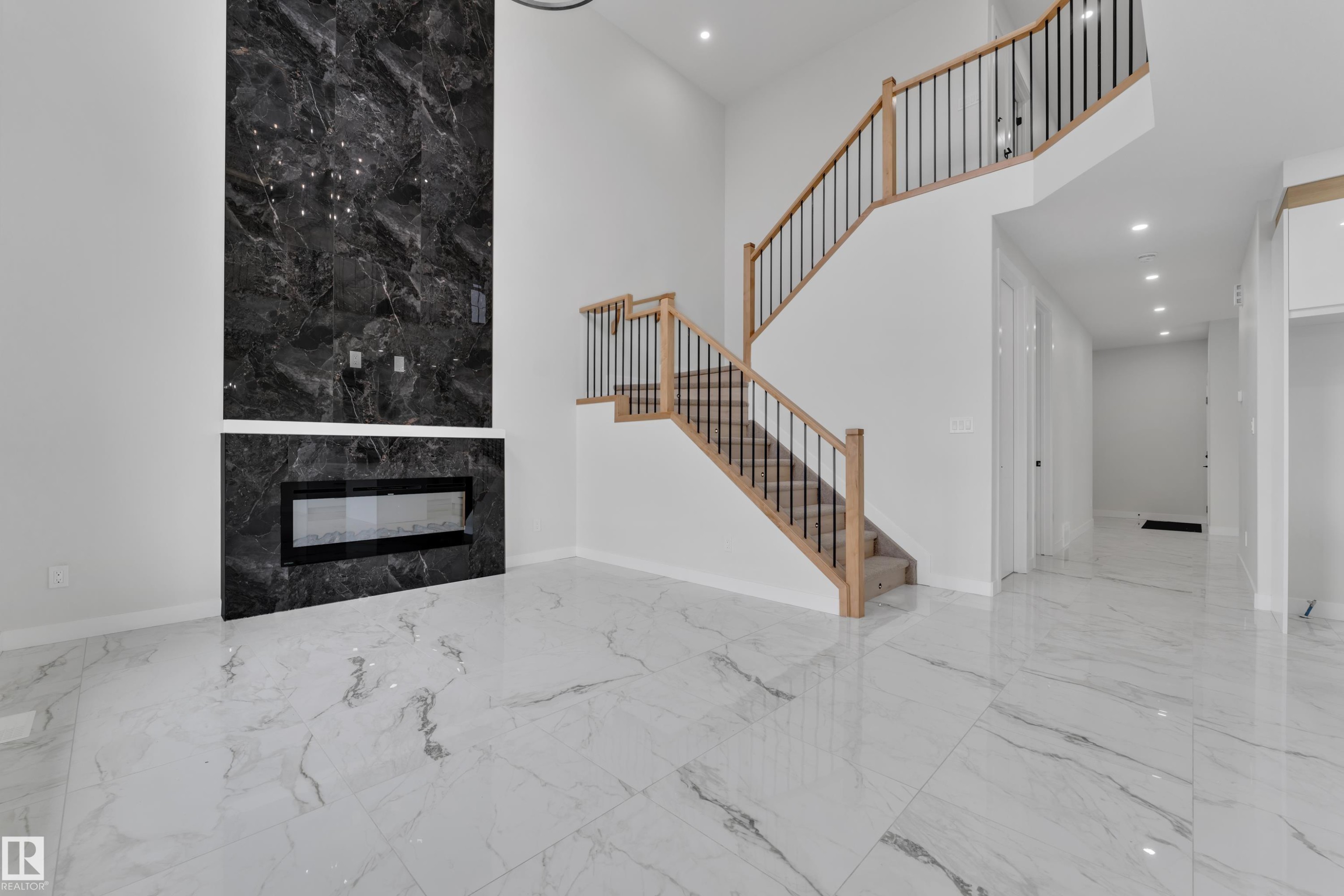 Two-story living area featuring a prominent black marble-finish fireplace wall with a linear electric fireplace - 12623 44 Street, Edmonton, AB