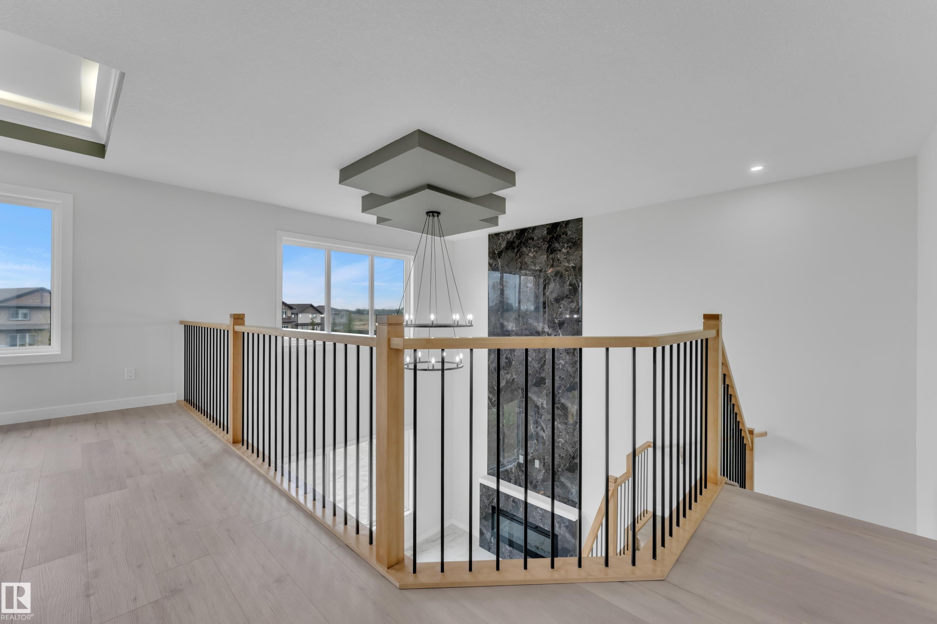 Upper-level landing featuring light wood-finish flooring and a contemporary chandelier - 12623 44 Street, Edmonton, AB