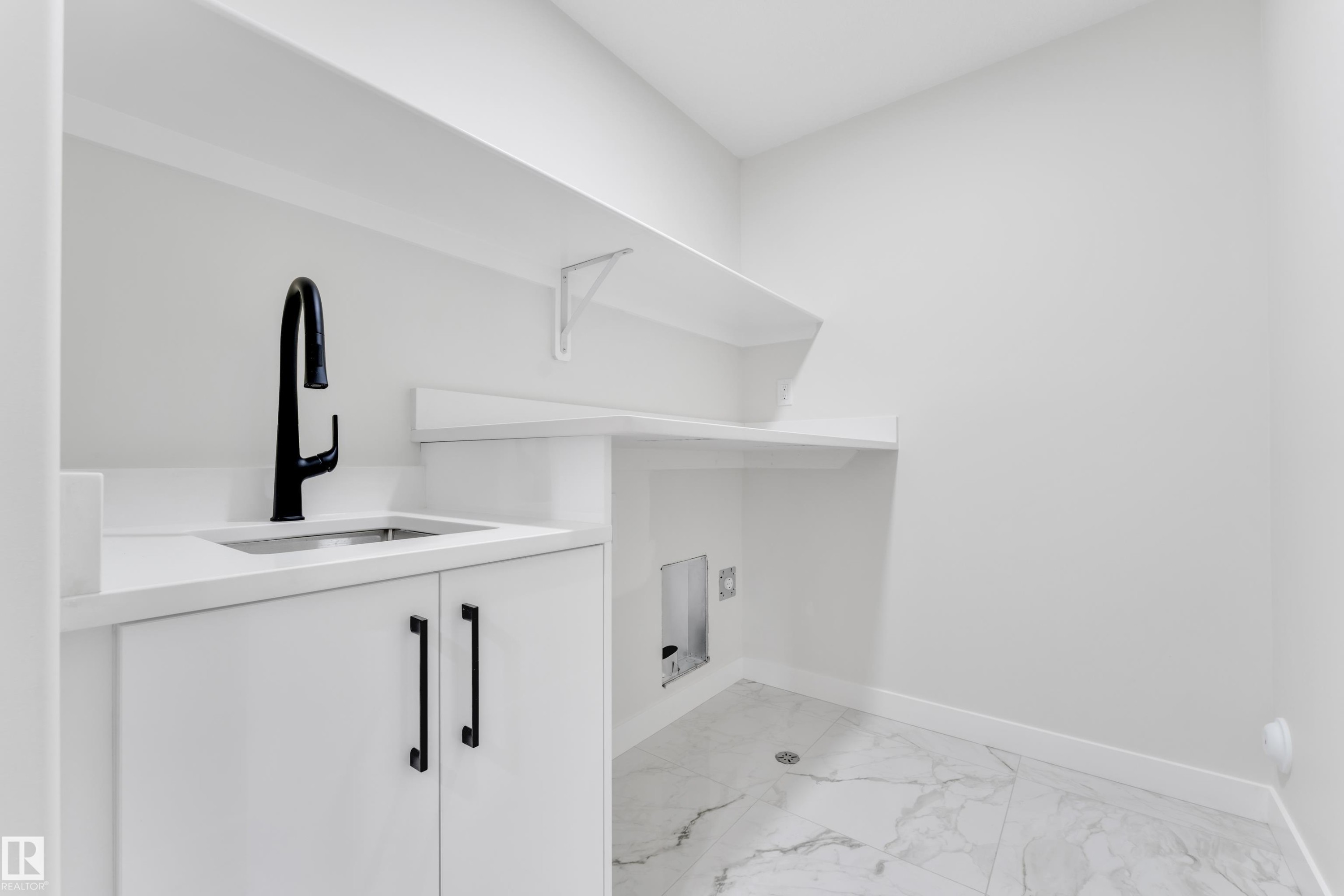 Utility room featuring a built-in sink with a matte black faucet, white cabinetry, and a light-toned countertop - 12623 44 Street, Edmonton, AB