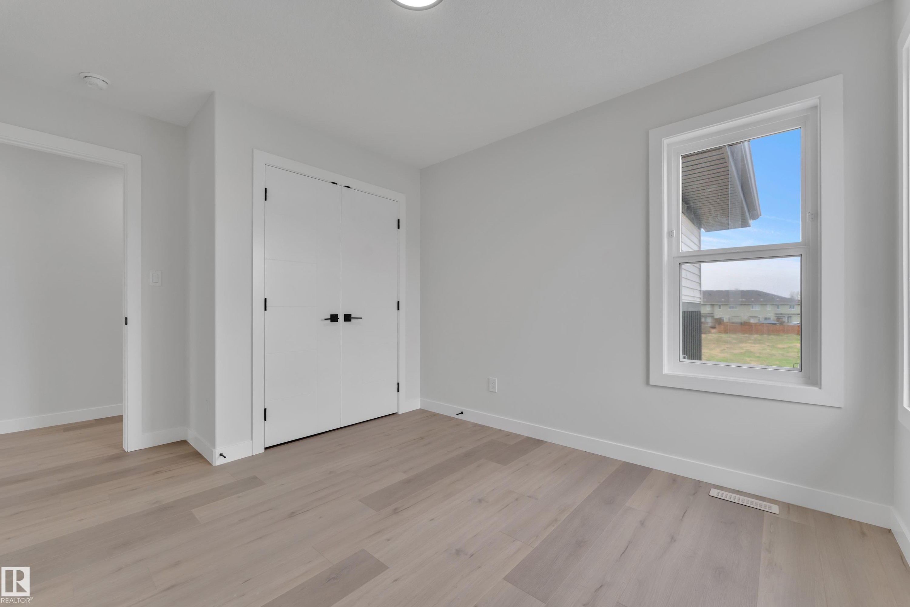 Light wood-finish flooring complements bright white walls and trim - 12623 44 Street, Edmonton, AB