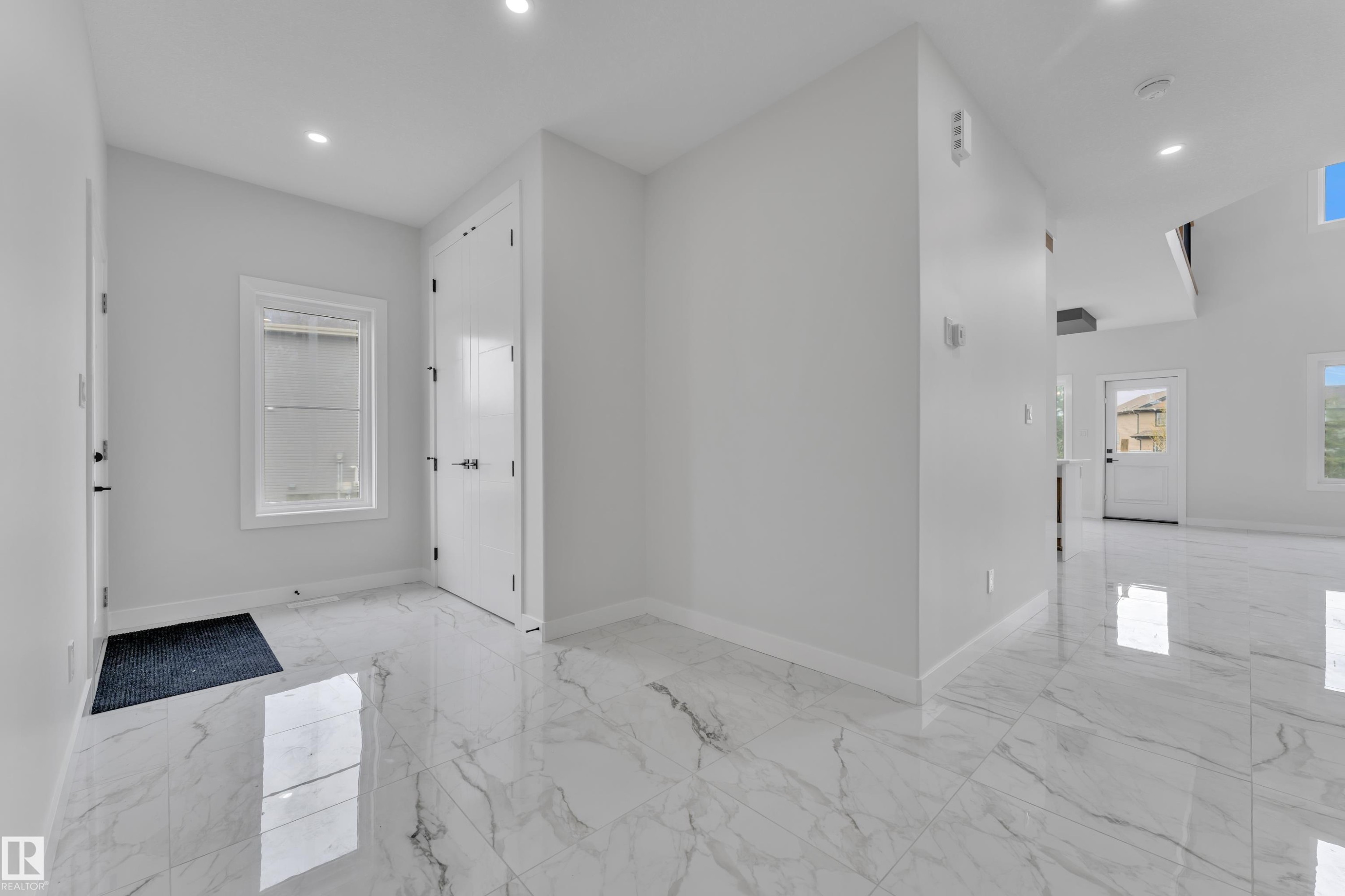 Entry foyer featuring large format tile flooring, recessed lighting, white walls, and a white paneled door - 12623 44 Street, Edmonton, AB