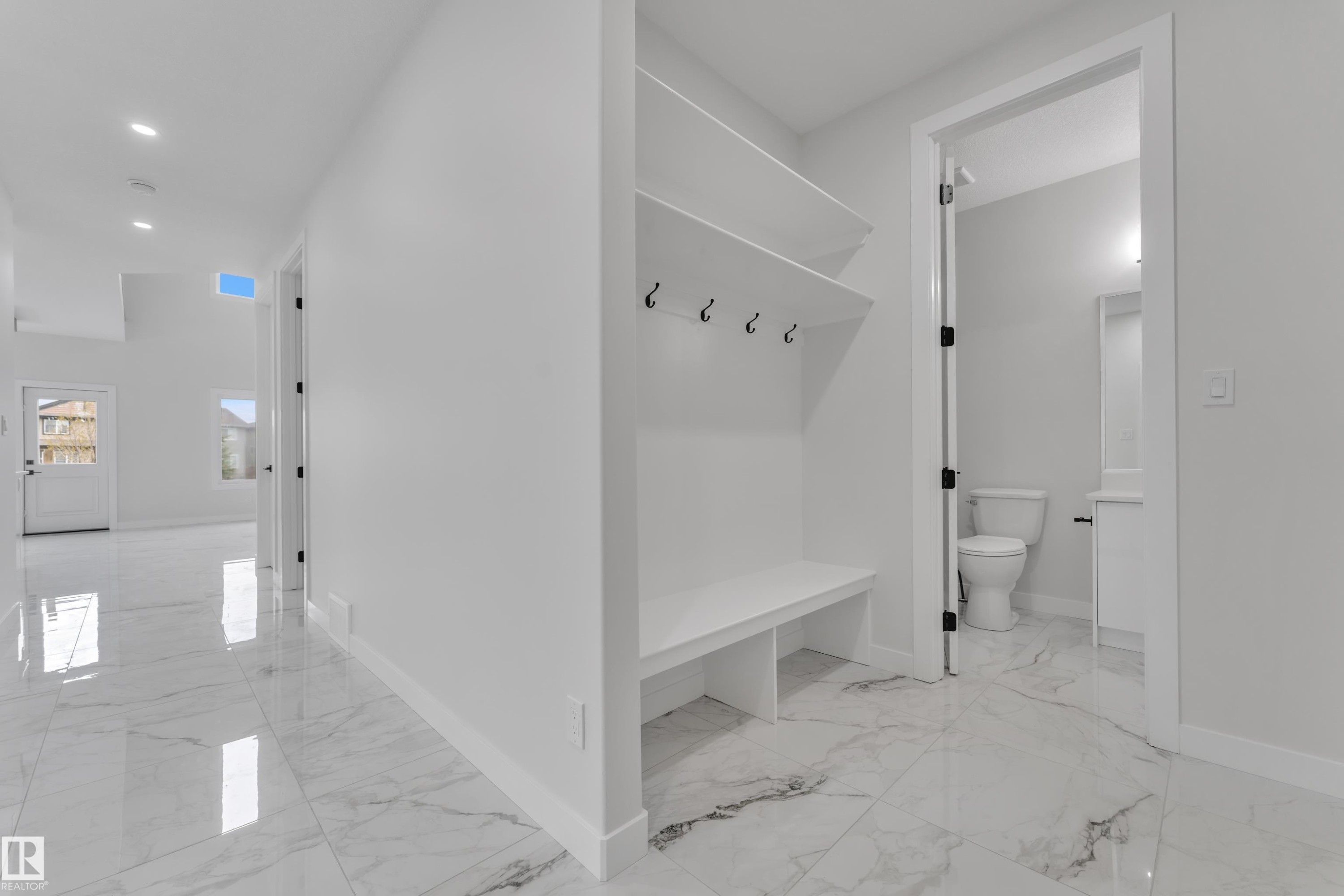 Entryway featuring large format marble-look tile flooring and a built-in bench with shelving and coat hooks - 12623 44 Street, Edmonton, AB