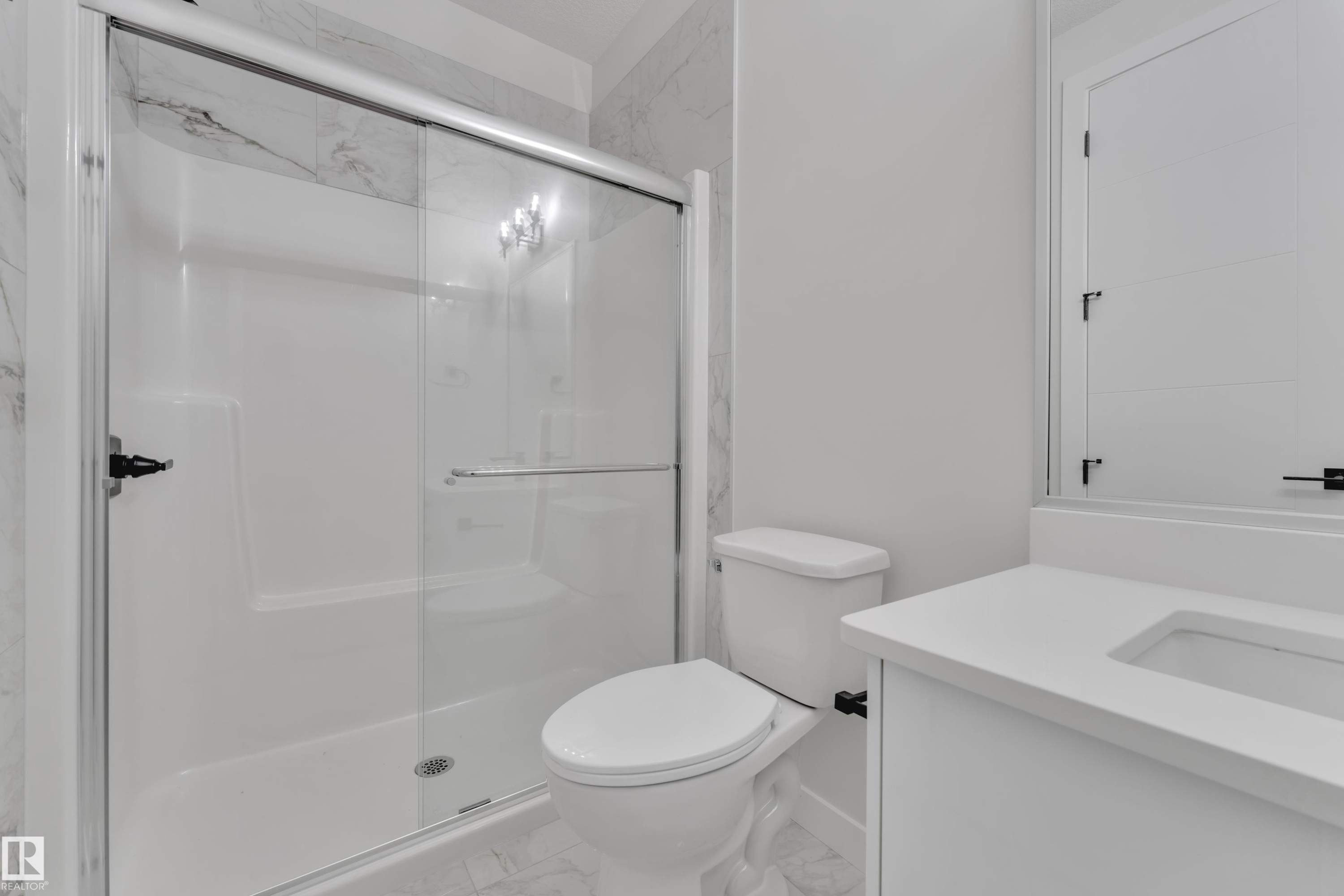 Bathroom featuring a glass-enclosed shower with white subway tile surround, white vanity with integrated sink, and large vanity mirror - 12623 44 Street, Edmonton, AB