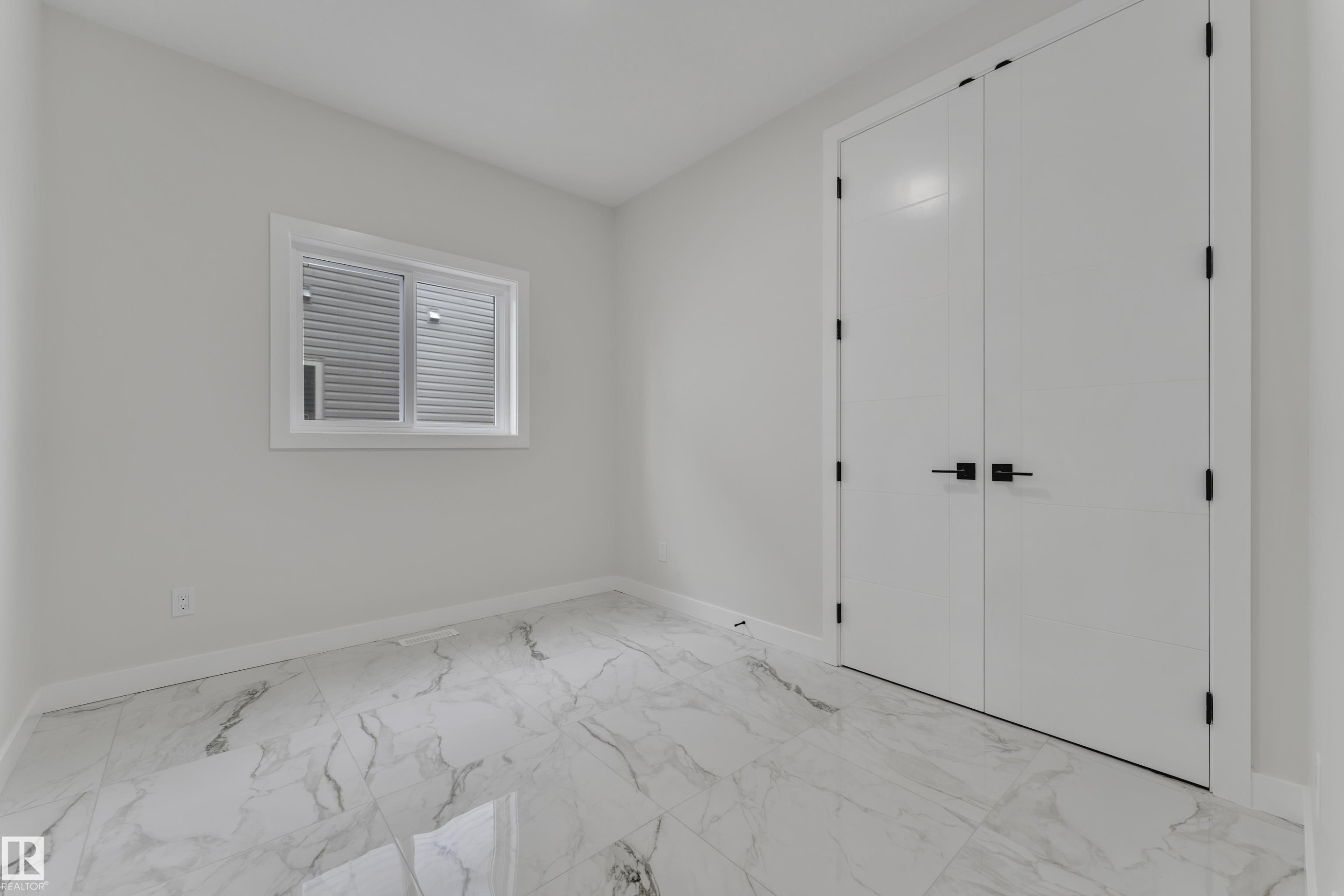 Spacious room featuring white walls, white baseboards, and marble-look tile flooring - 12623 44 Street, Edmonton, AB