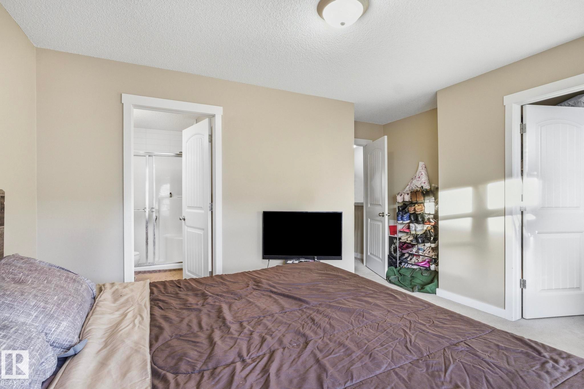 Neutral-toned room with white trim, featuring an open doorway revealing a shower enclosure - 30 6075 Schonsee Way, Edmonton, AB - Indoor Photo Showing Bedroom