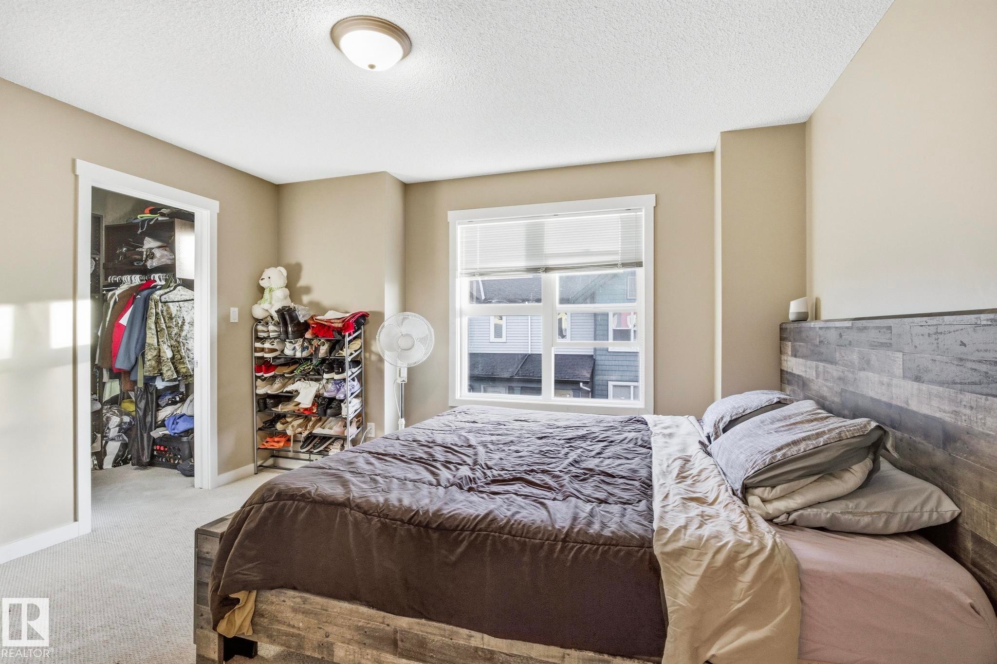 Bedroom featuring a large window with blinds, carpeted flooring, and a flush-mount ceiling light - 30 6075 Schonsee Way, Edmonton, AB - Indoor Photo Showing Bedroom