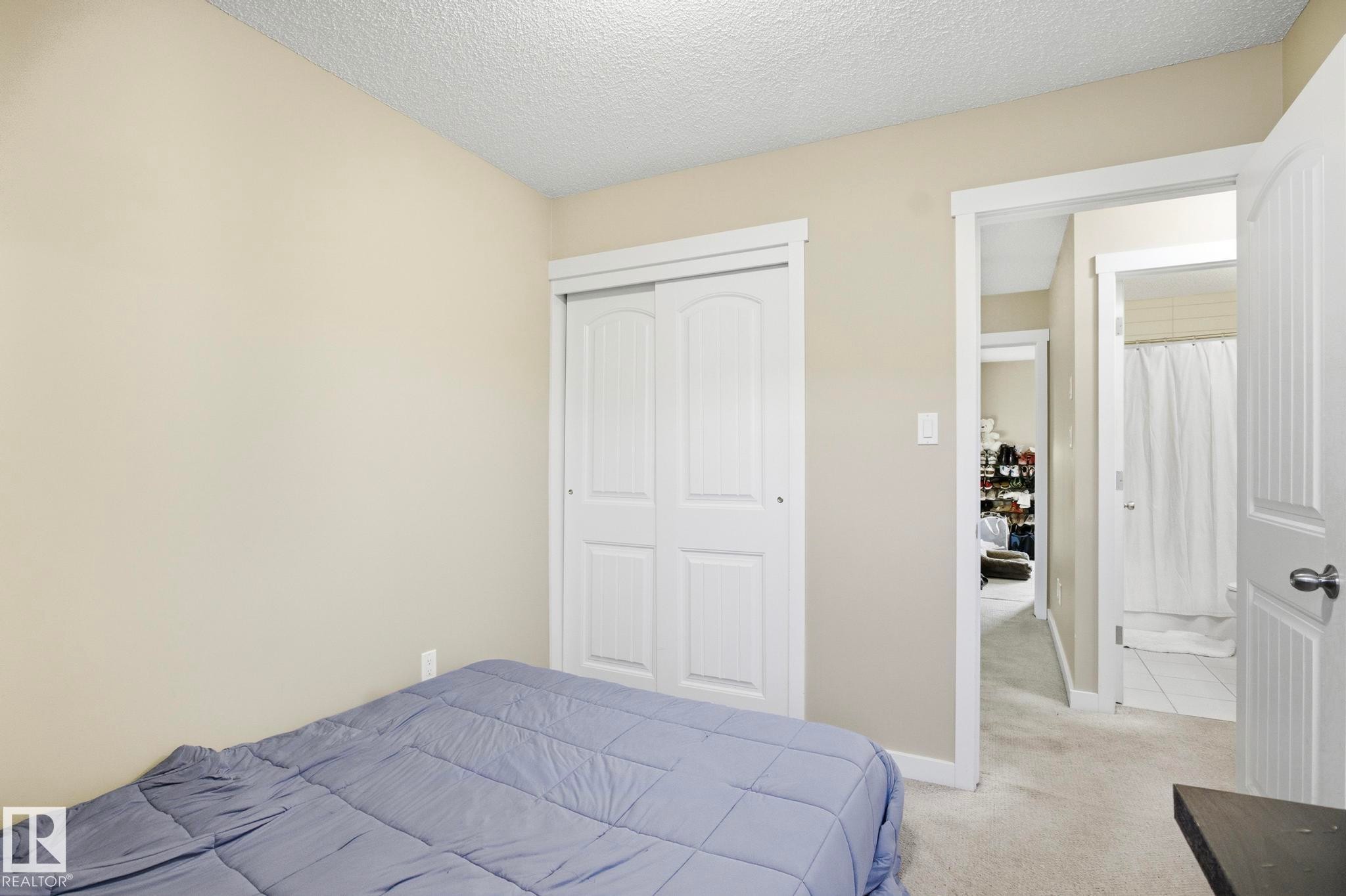 Neutral-toned bedroom featuring carpet flooring and a textured ceiling - 30 6075 Schonsee Way, Edmonton, AB - Indoor Photo Showing Bedroom
