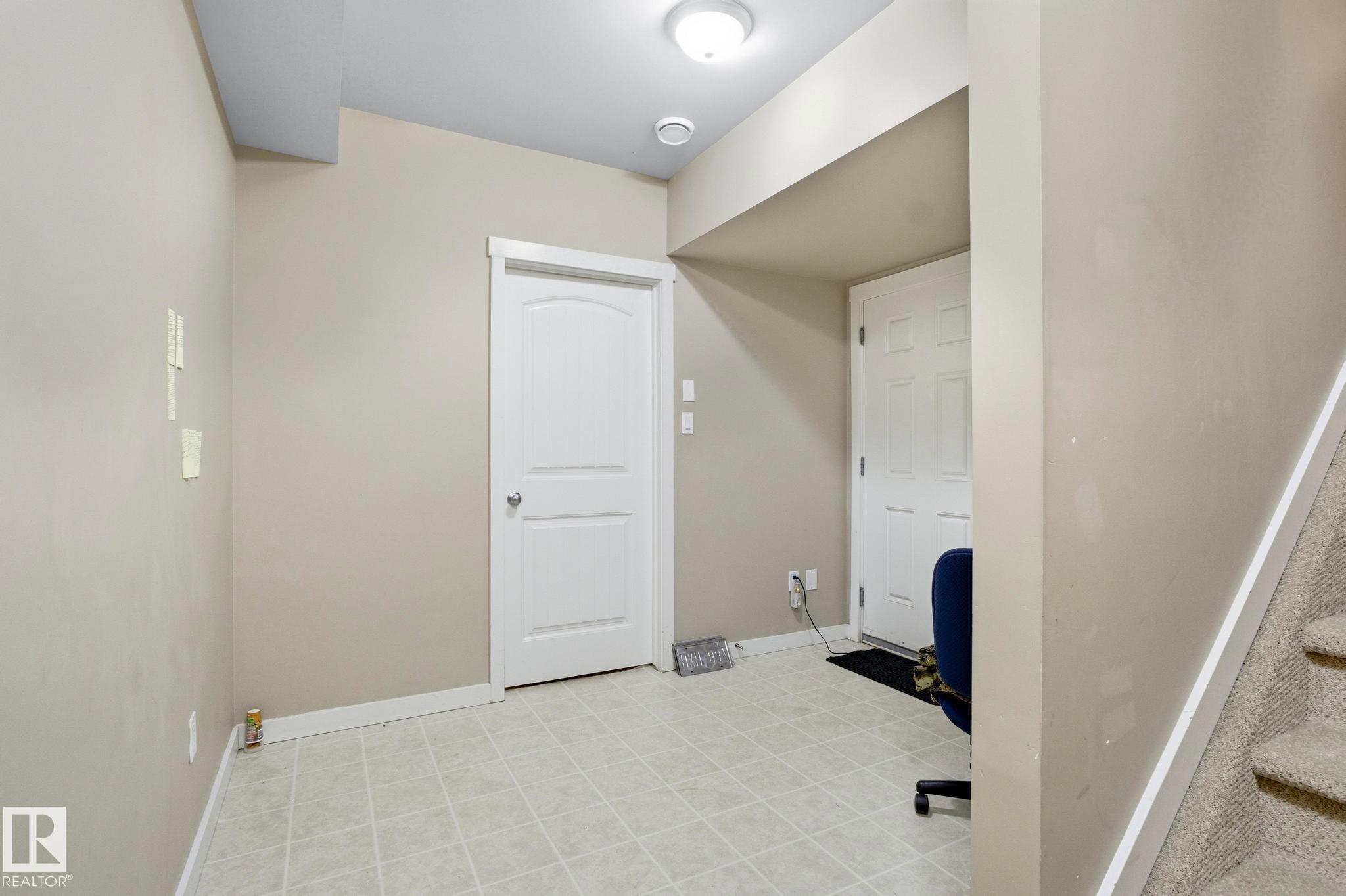 Neutral-toned room featuring light-colored square tile flooring and white baseboards - 30 6075 Schonsee Way, Edmonton, AB - Indoor Photo Showing Other Room