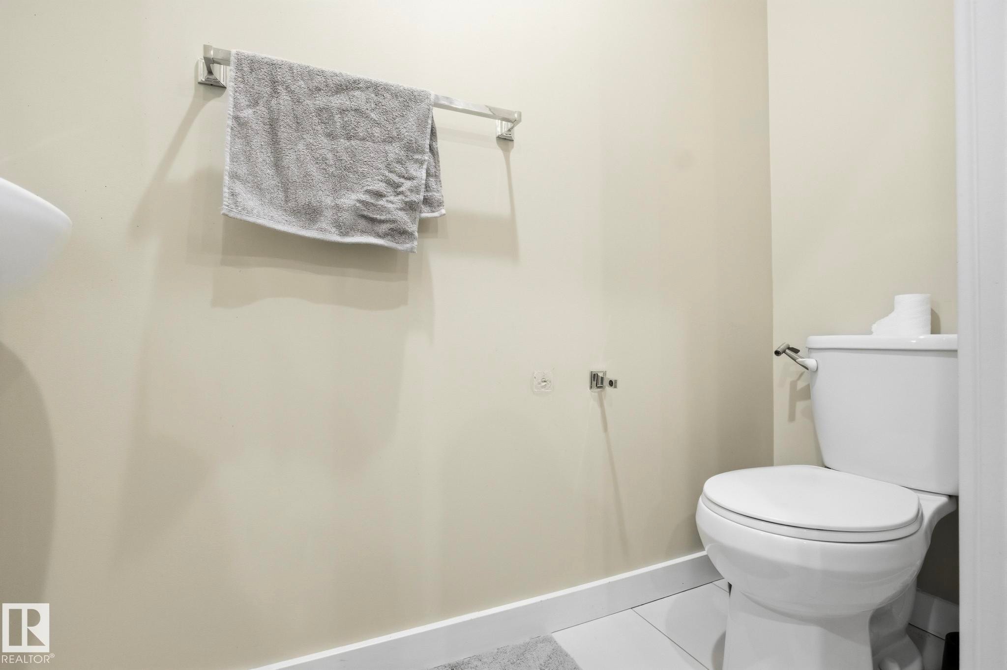 White ceramic toilet with polished chrome hardware - 30 6075 Schonsee Way, Edmonton, AB - Indoor Photo Showing Bathroom