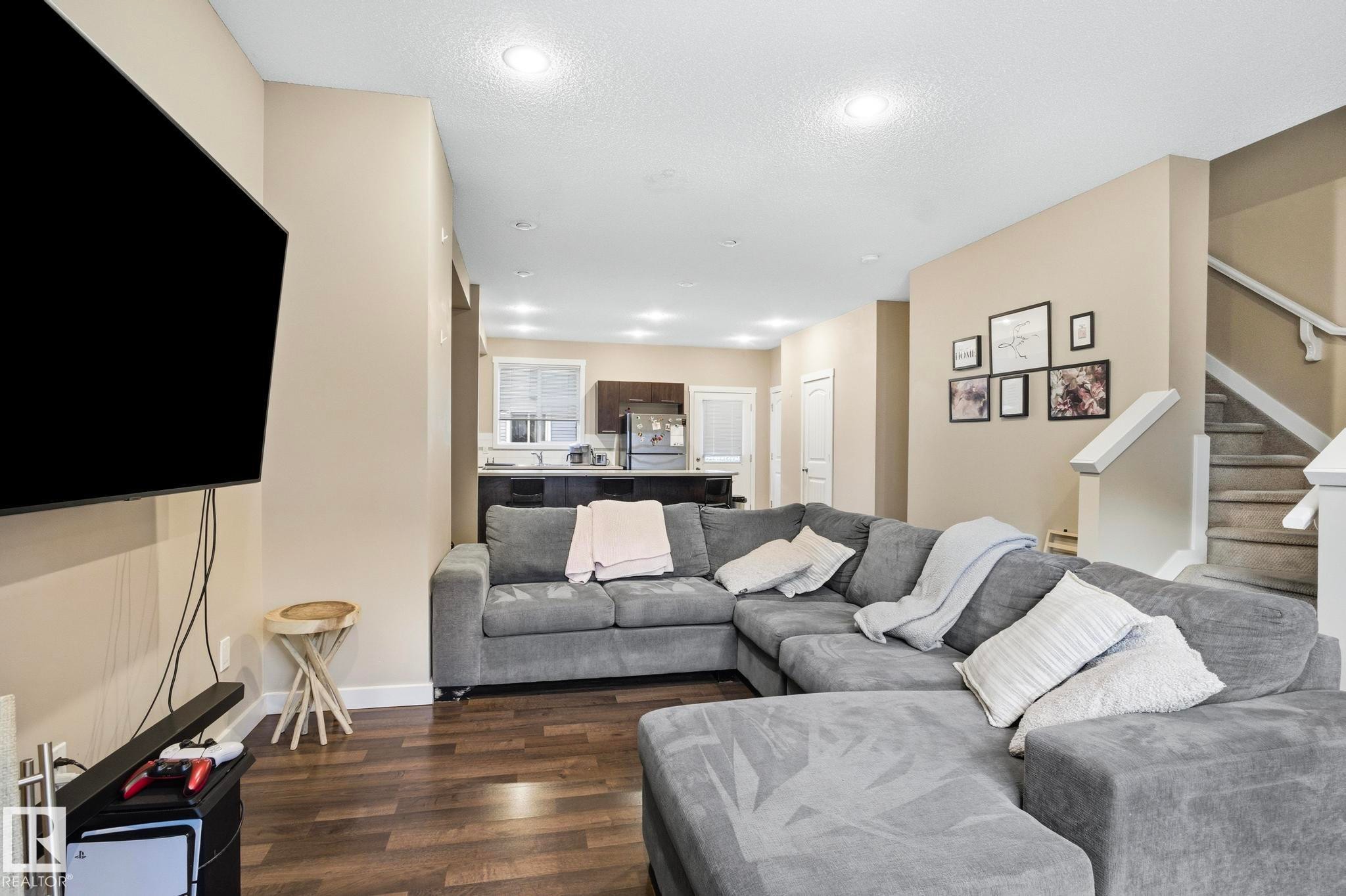 Open-concept living area featuring wood-finish flooring, recessed lighting, and a neutral color palette - 30 6075 Schonsee Way, Edmonton, AB - Indoor Photo Showing Living Room