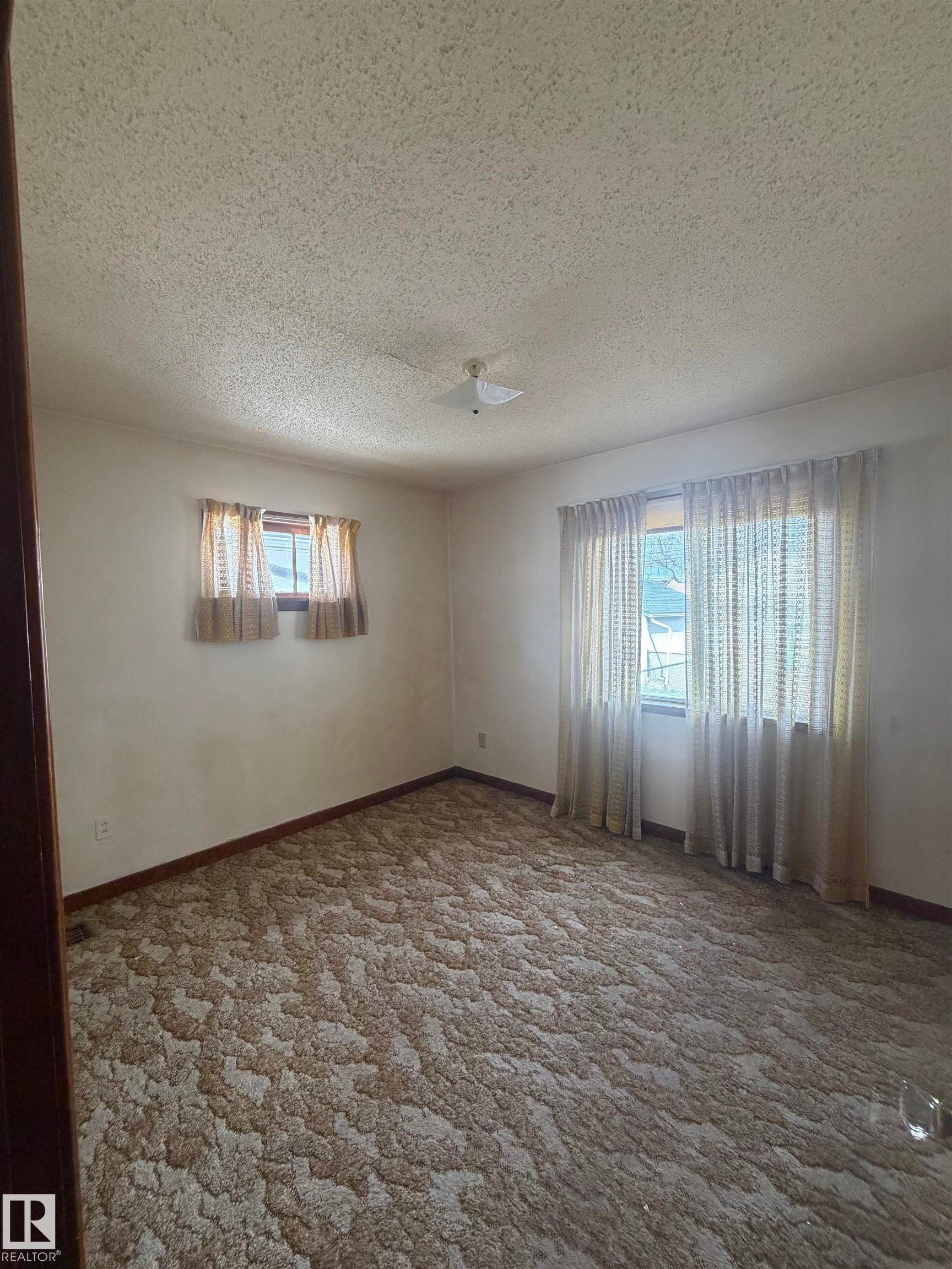 Spacious room featuring patterned carpeting, white walls, and a textured ceiling - 9630 106 Avenue, Edmonton, AB - Indoor Photo Showing Other Room