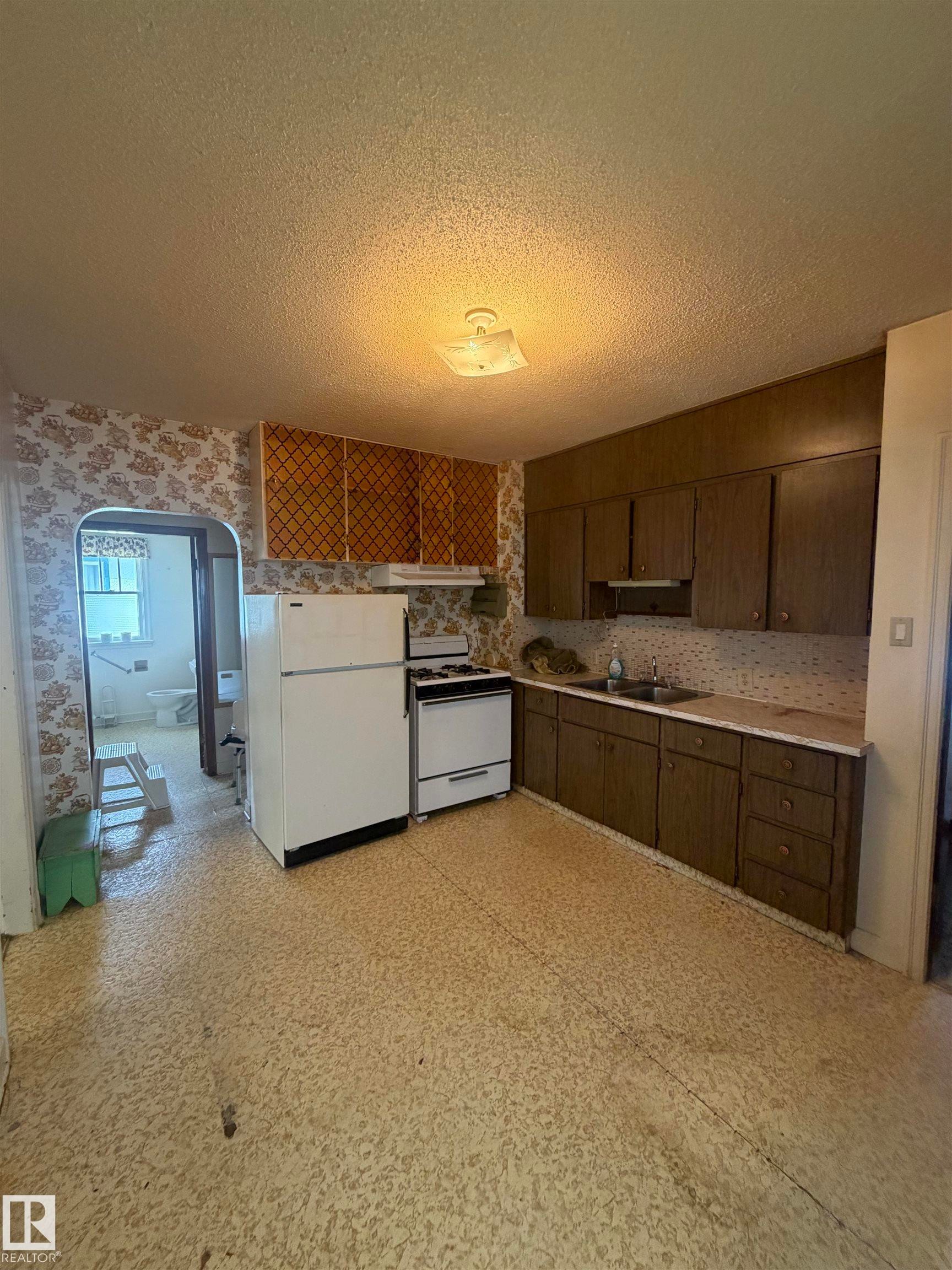 Kitchen featuring wood-finish cabinetry, laminate countertops, and a white appliance suite - 9630 106 Avenue, Edmonton, AB - Indoor Photo Showing Kitchen