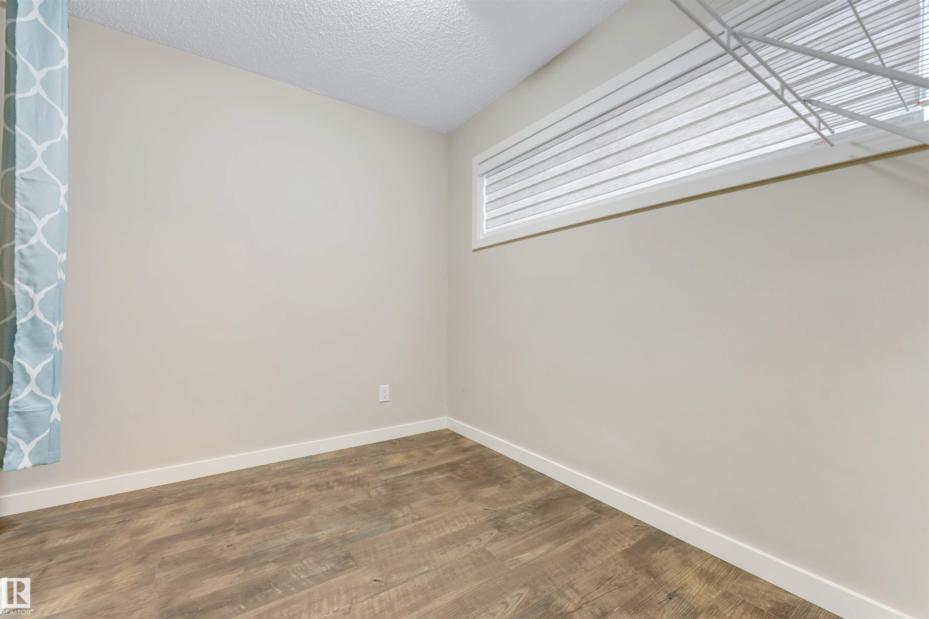 Room featuring wood-finish flooring, neutral wall paint, and white baseboards - 3340 15A Avenue, Edmonton, AB - Indoor Photo Showing Other Room