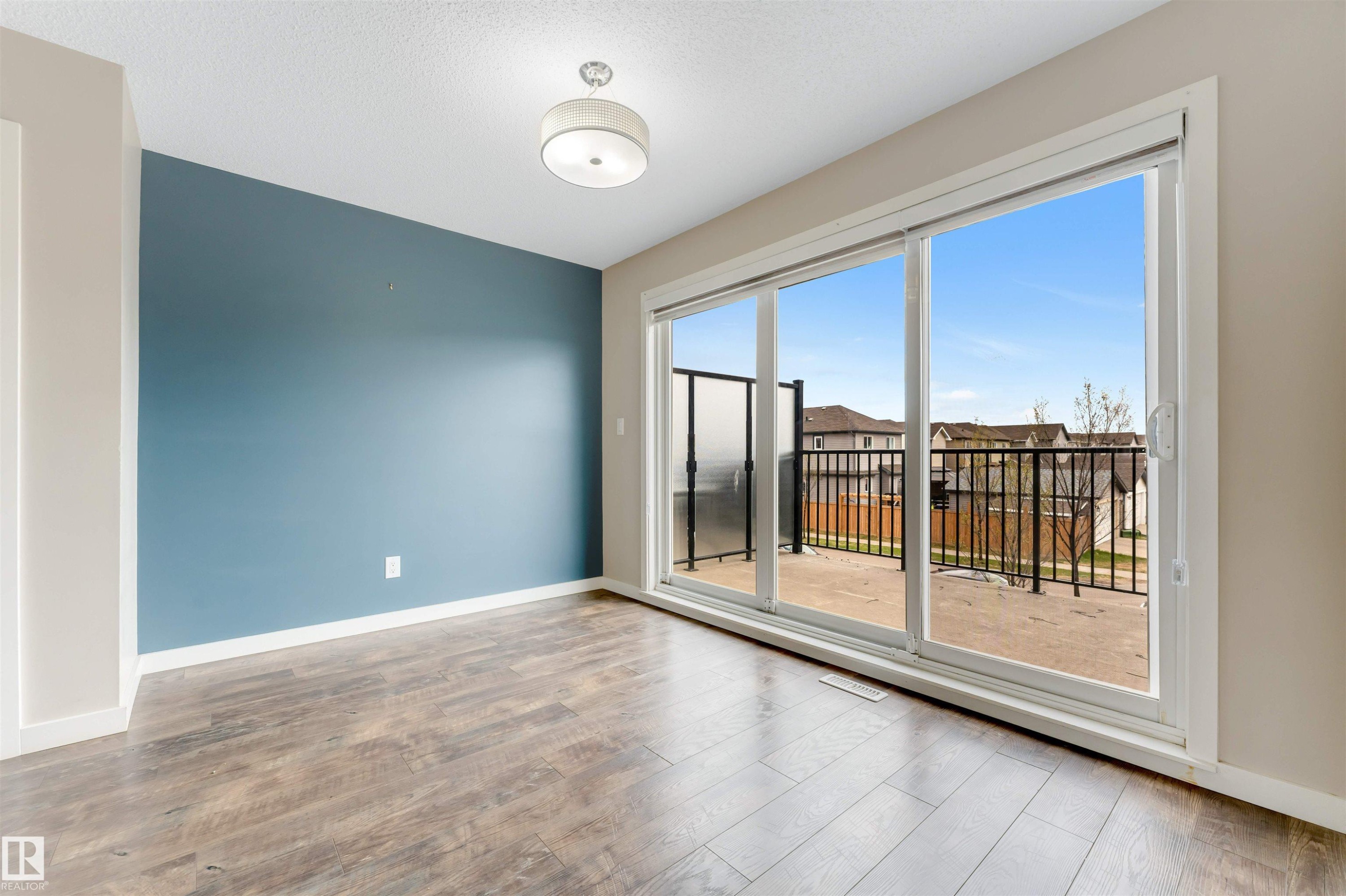 Sliding glass doors opening to an exterior balcony with black metal railings - 3340 15A Avenue, Edmonton, AB - Indoor Photo Showing Other Room