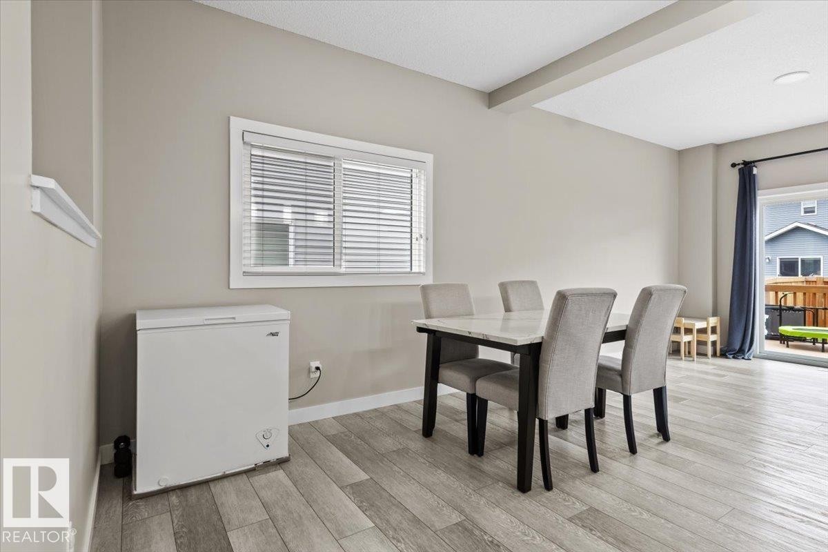 Open concept living area featuring light wood-finish flooring, a contemporary window with blinds, and a sliding glass door leading to an outdoor space - 236 39 Avenue, Edmonton, AB - Indoor Photo Showing Dining Room