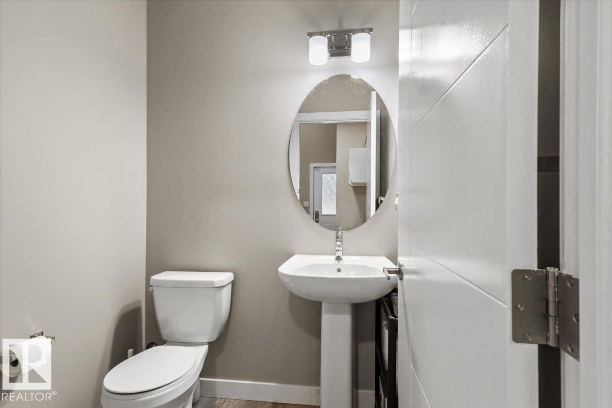 Pedestal sink with chrome faucet, oval mirror, and contemporary two-light vanity fixture - 236 39 Avenue, Edmonton, AB - Indoor Photo Showing Bathroom