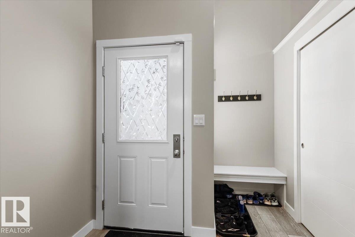 Entryway featuring a white paneled door with decorative glass, a built-in bench, a coat rack with five hooks, and wood-finish flooring - 236 39 Avenue, Edmonton, AB - Indoor Photo Showing Other Room