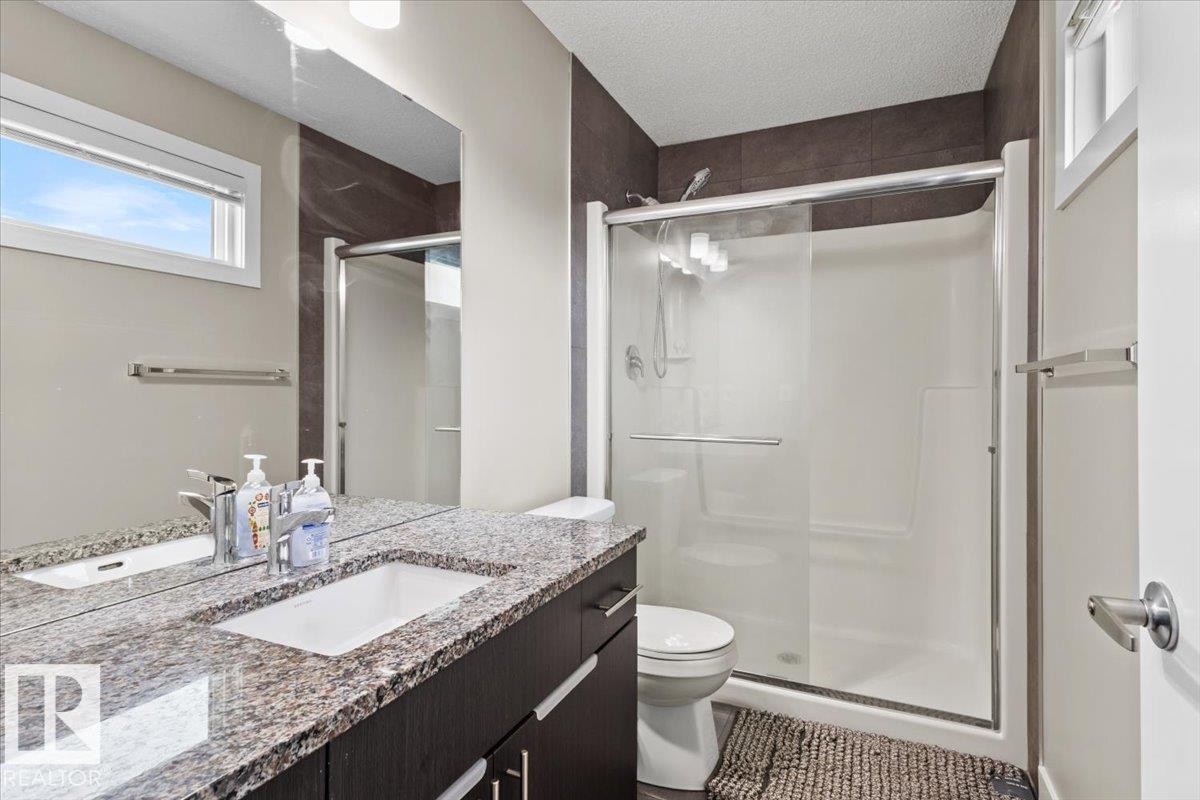 Bathroom featuring a dark wood-finish vanity with a light granite countertop, an undermount sink, and a large wall-mounted mirror - 236 39 Avenue, Edmonton, AB - Indoor Photo Showing Bathroom