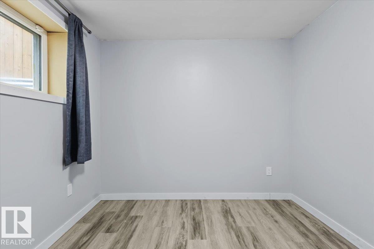Room featuring light wood-finish flooring, white baseboards, and a window with a white frame - 236 39 Avenue, Edmonton, AB - Indoor Photo Showing Other Room